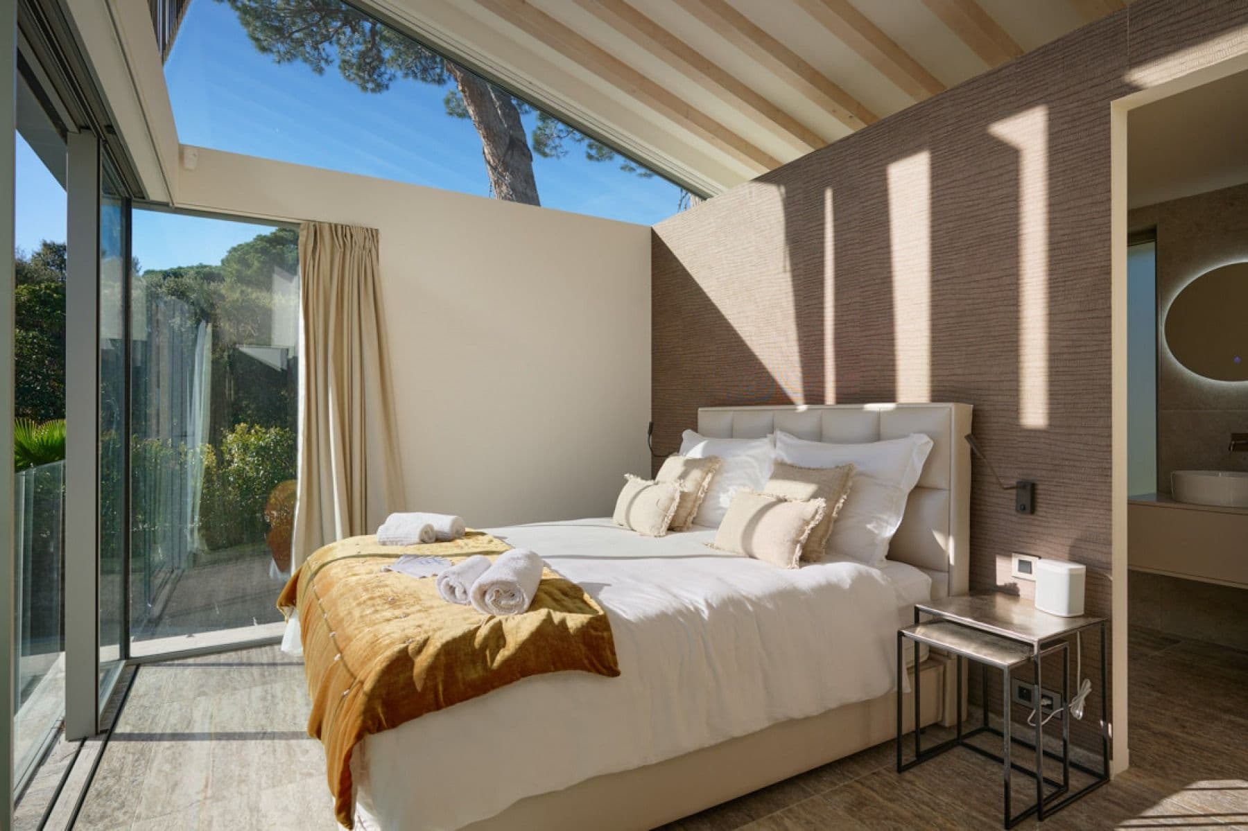 Bedroom with skylight, glass-walled ensuite and garden views
