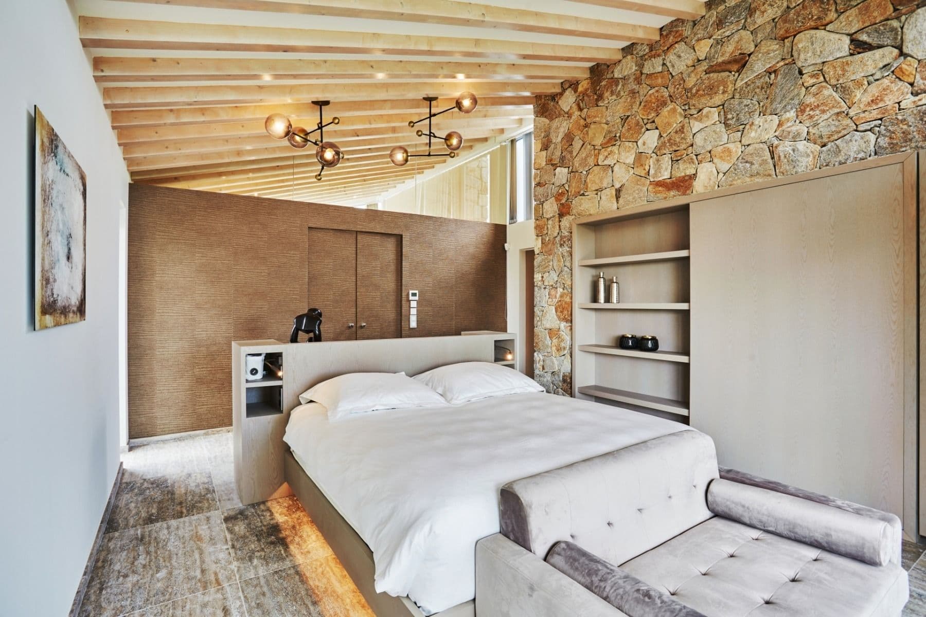 Bedroom with stone wall, beamed ceiling and built-in wardrobe