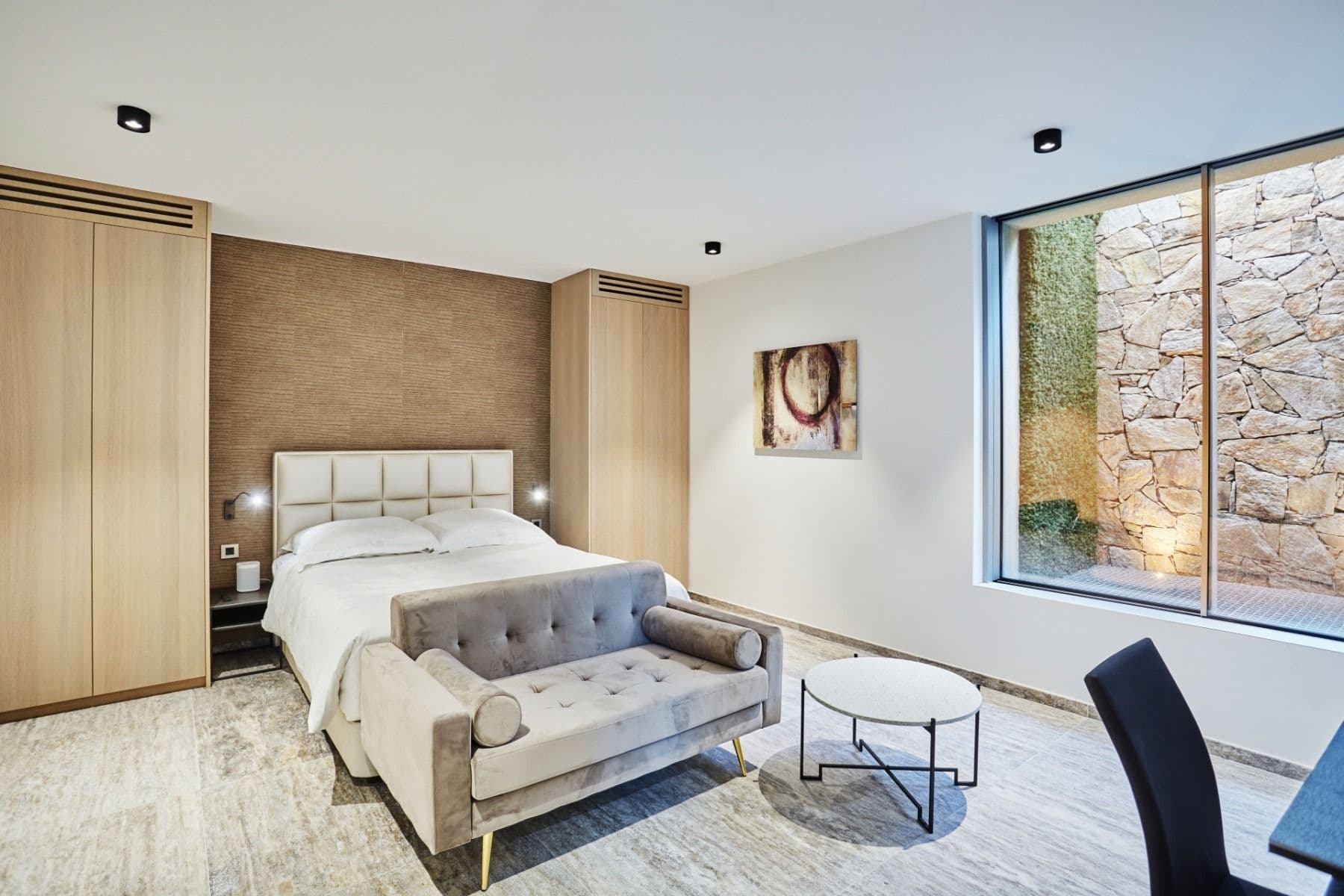 Bedroom with exposed stone feature wall and artwork above the headboard
