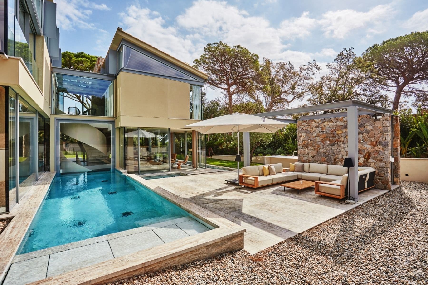 Private swimming pool and stone terrace with lounge seating beside the villa