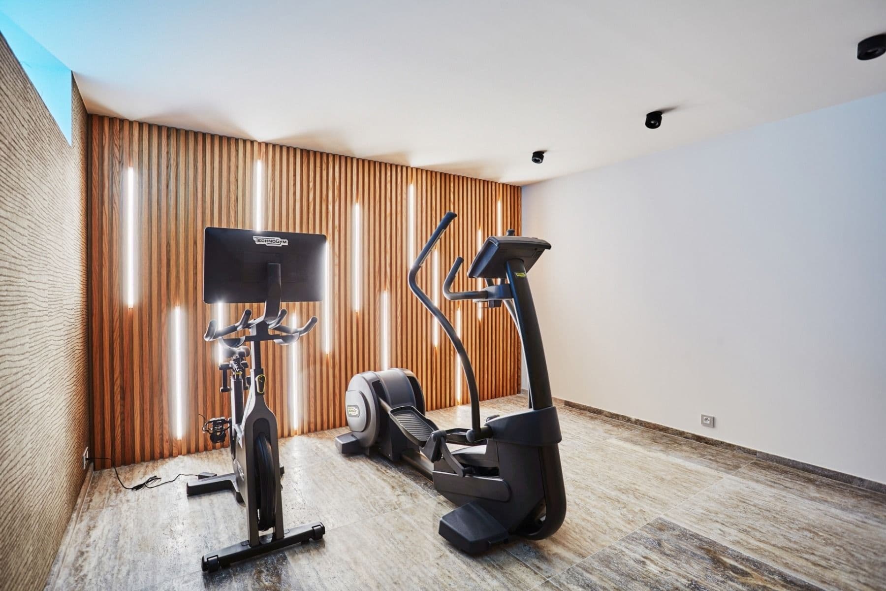 Private home gym with cardio machines and wood-slat feature wall