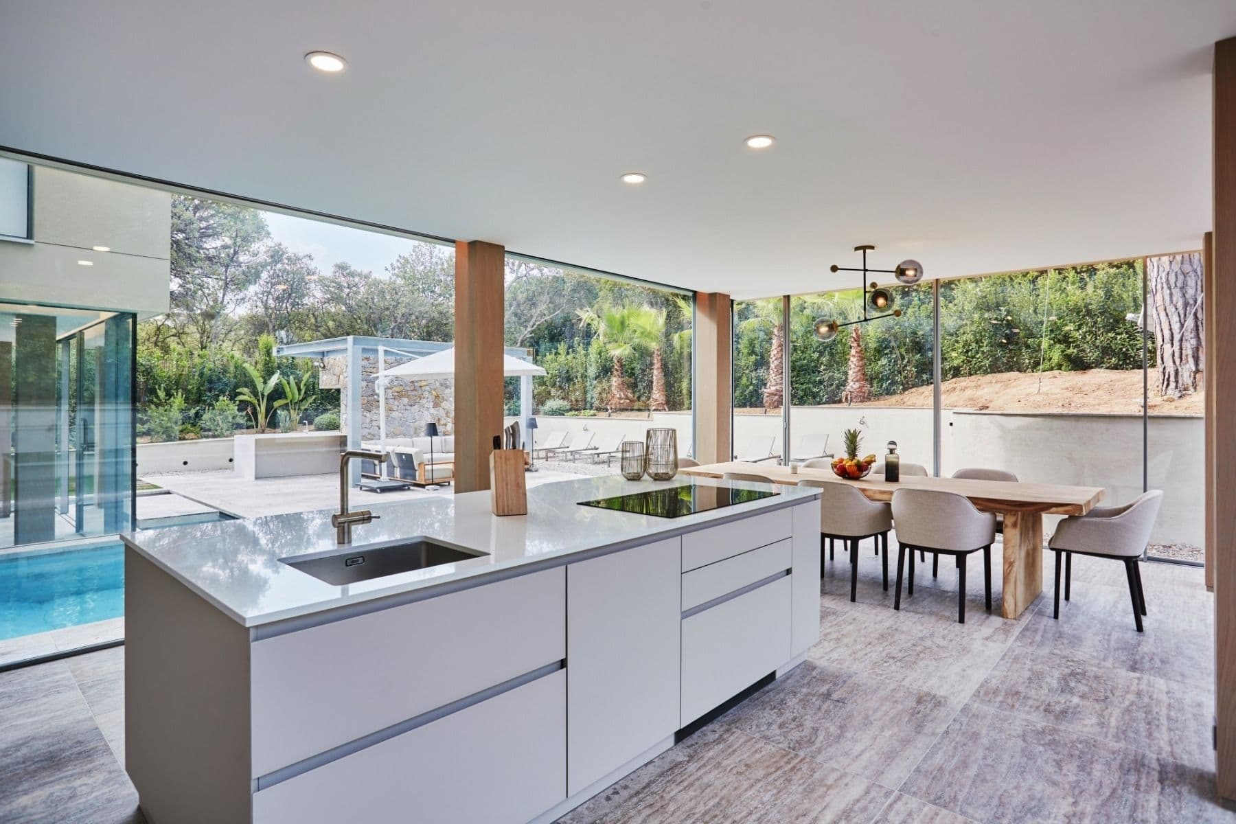Contemporary white kitchen with central island and glass doors to the terrace