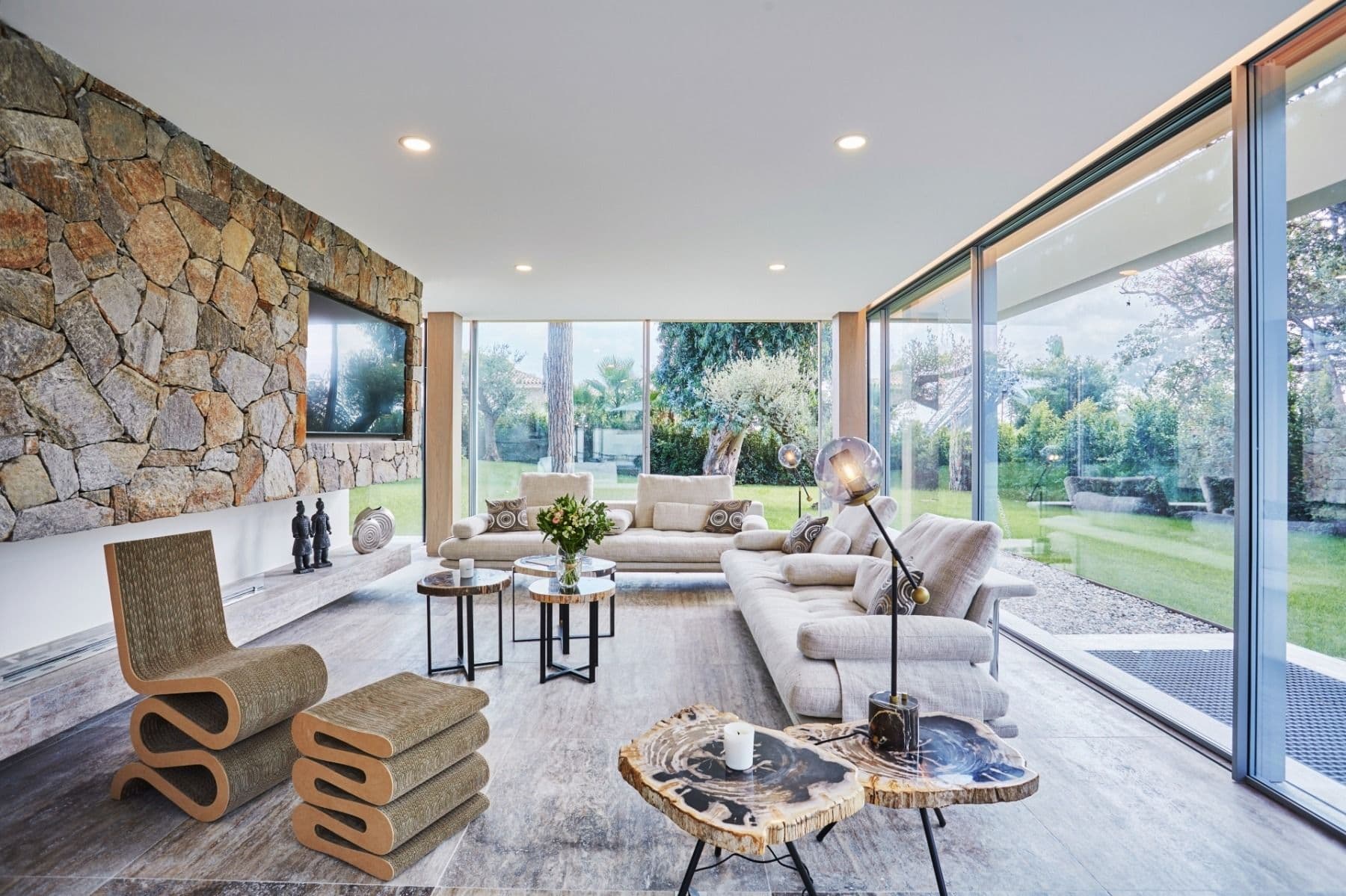 Bright open-plan living room with floor-to-ceiling windows onto the garden and neutral sofas
