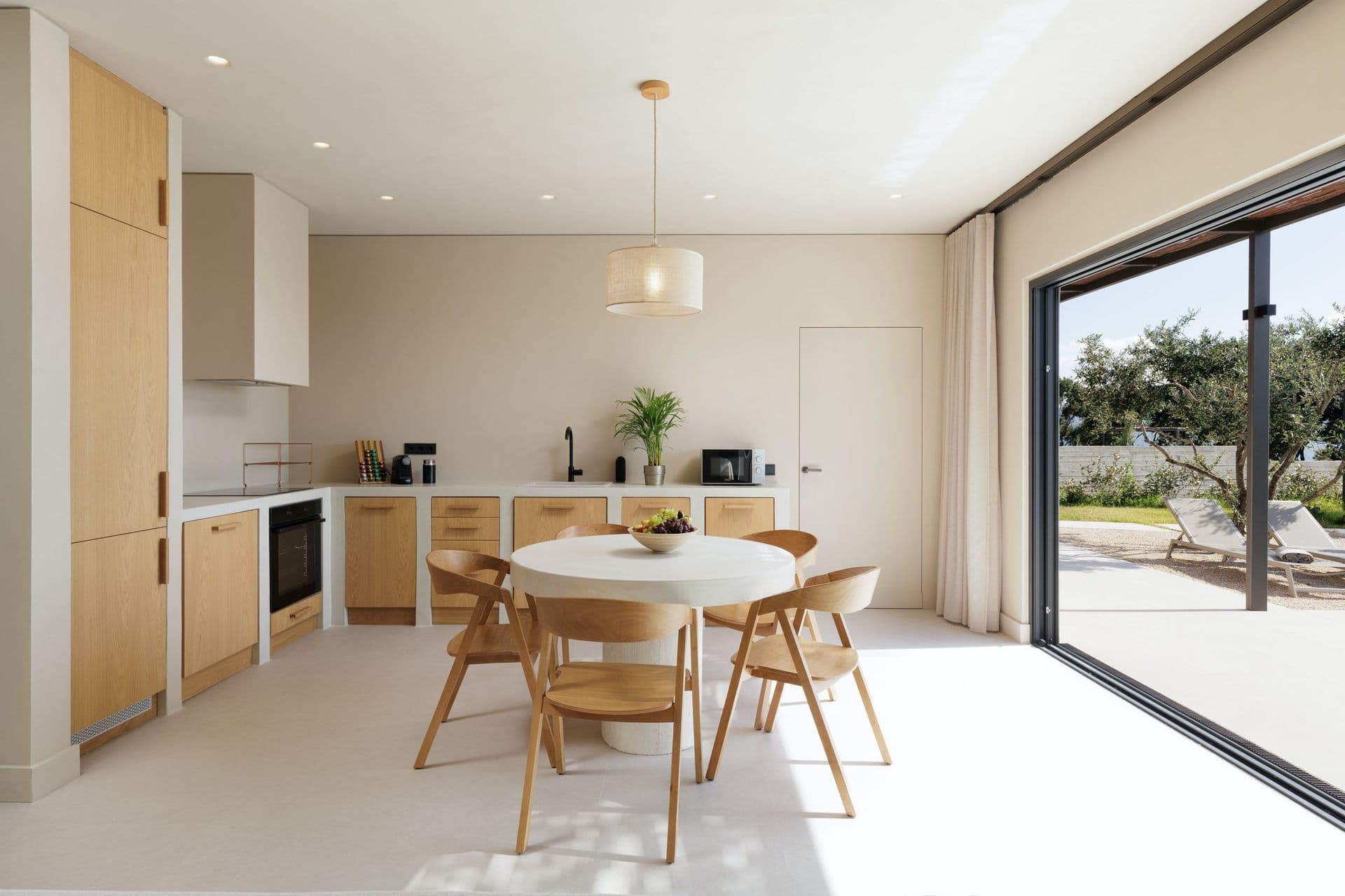 Oak kitchen with a round dining table opening to the terrace at Corfu Dreams, Corfu