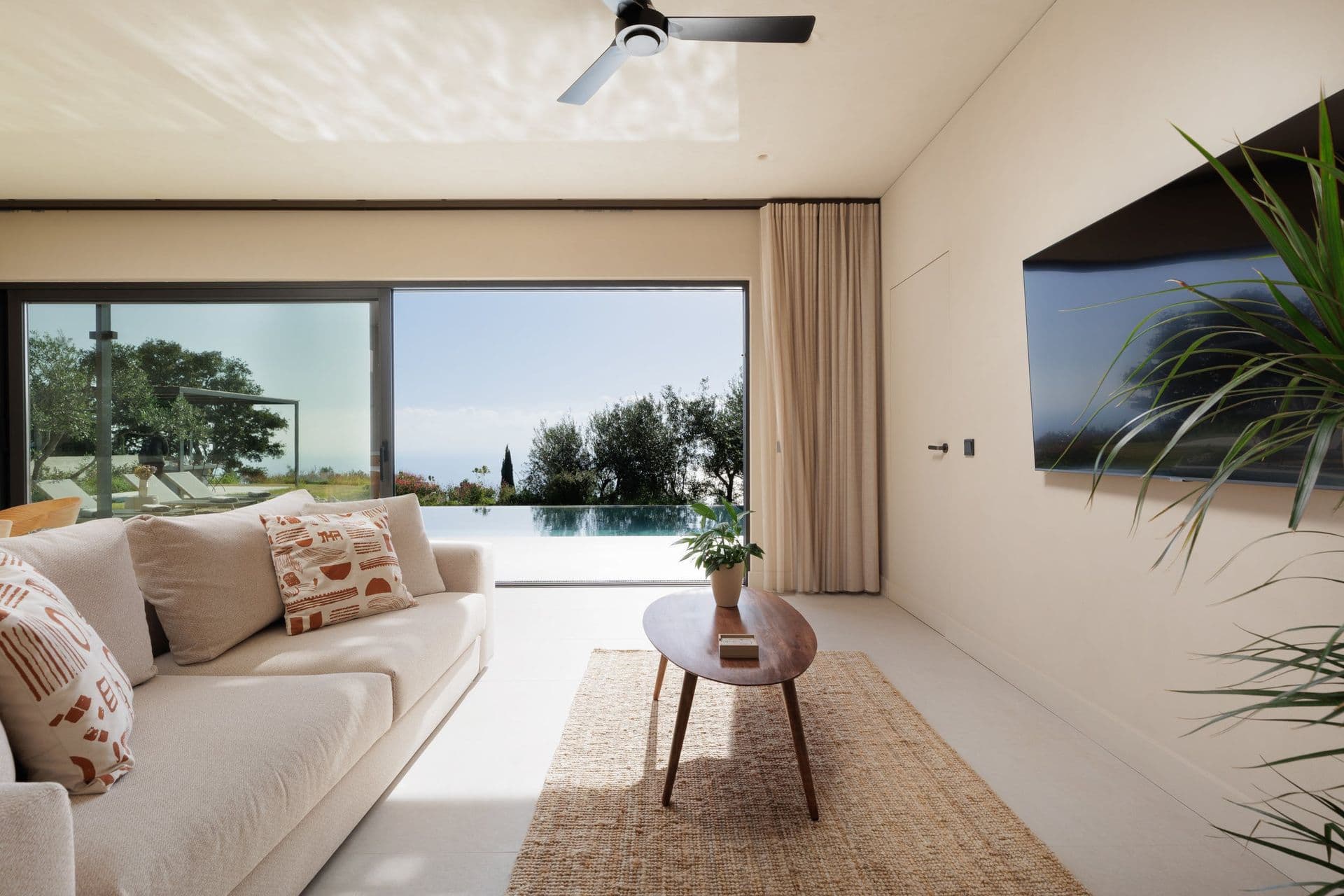 Living room with a cream sofa opening to the pool and sea at Corfu Dreams, Corfu