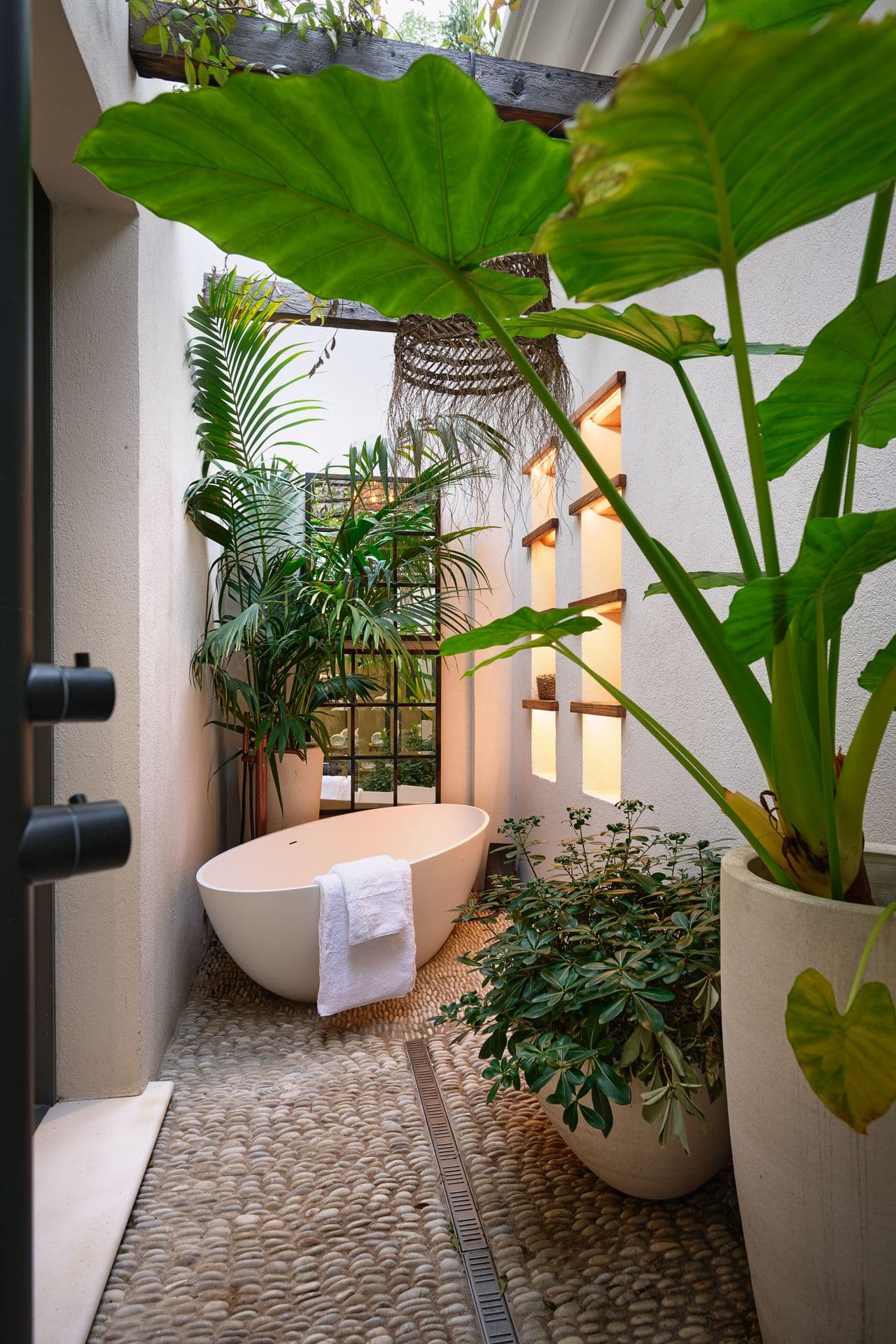 A freestanding bath set in a private courtyard among lush tropical planting
