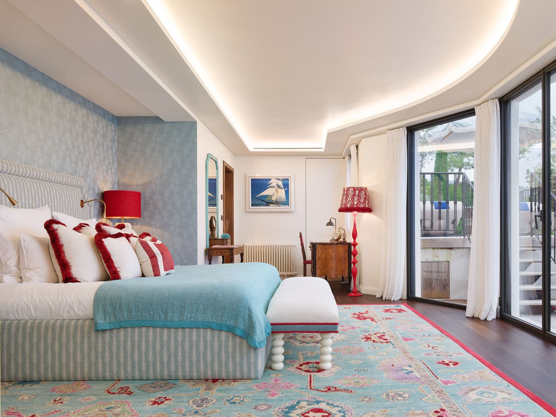 A patterned bedroom with red and white accents and a garden facing terrace
