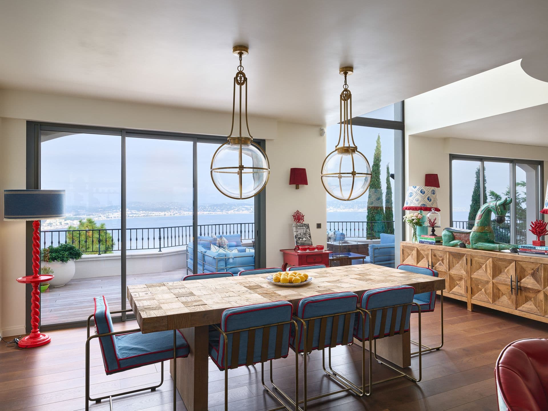 A dining table set beneath pendant lights with full length sea view windows