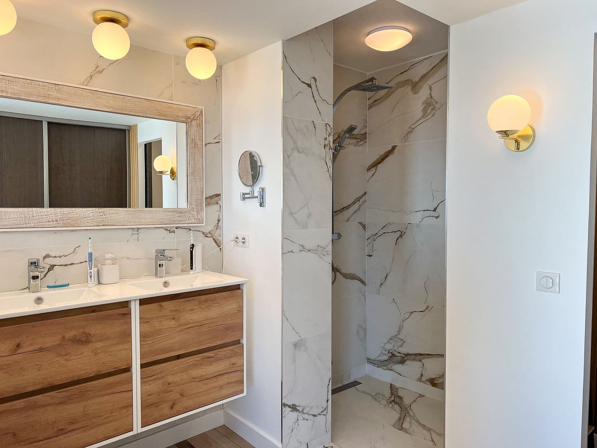 Bathroom with a wood double vanity and marble-tiled shower at Southern Beauty