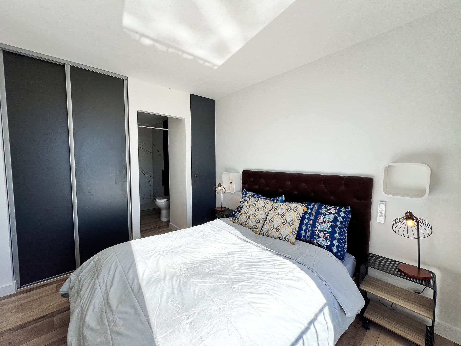 Bedroom with a dark tufted headboard and blue accents at Southern Beauty