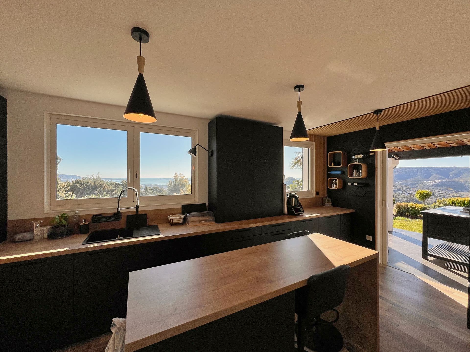 Dark kitchen with a wood breakfast bar and hillside views at Southern Beauty