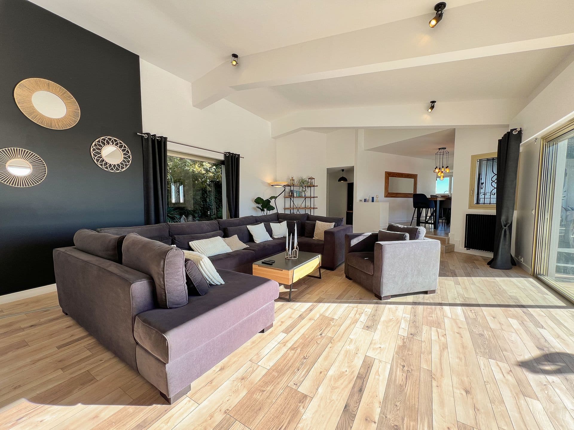 Living room with a black accent wall and round mirrors at Southern Beauty