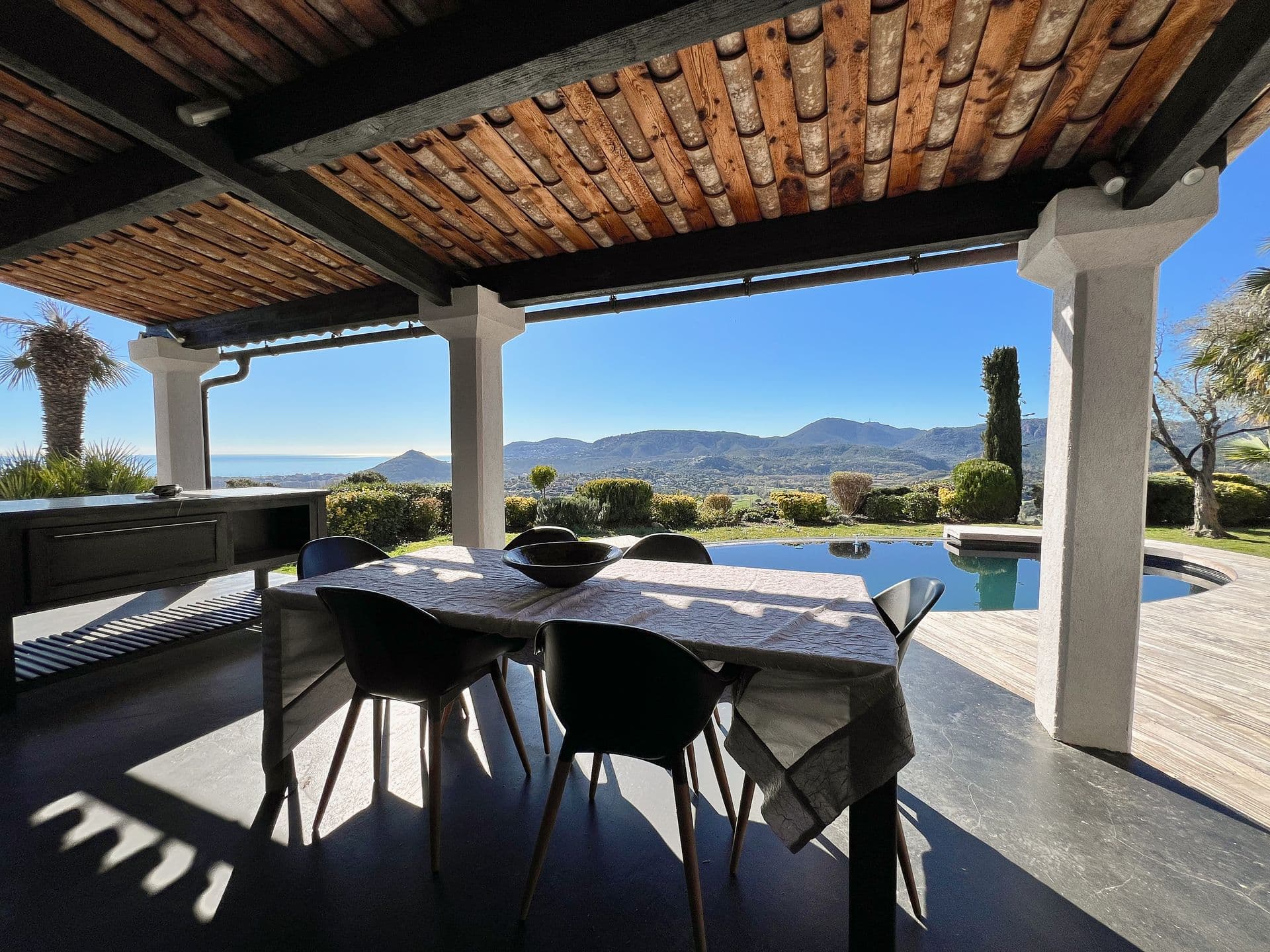 Covered terrace dining beneath a wood-beamed pergola with mountain views at Southern Beauty