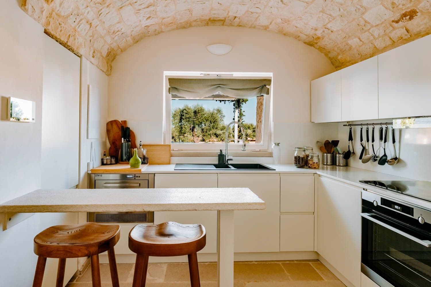 Trullo Acanto kitchen island with breakfast bar beneath stone vault, Cisternino, Puglia, Italy