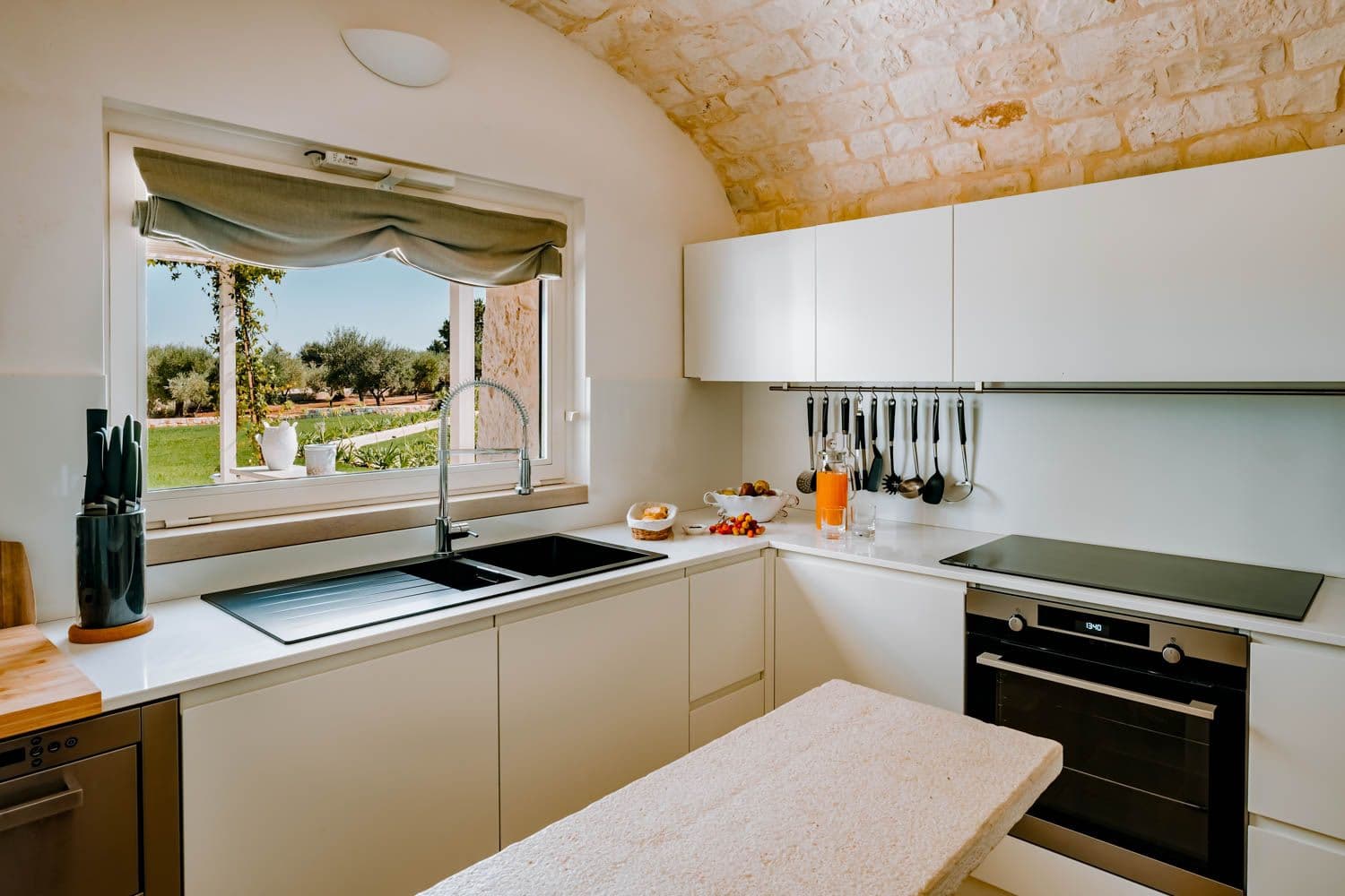 Trullo Acanto modern kitchen with vaulted stone ceiling and olive grove views, Cisternino, Puglia, Italy