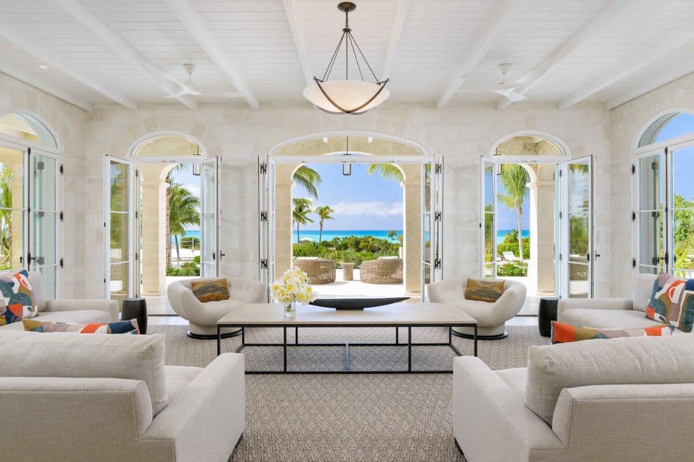 Living room with arched doors opening to the beach and sea at Sea Breeze Estate