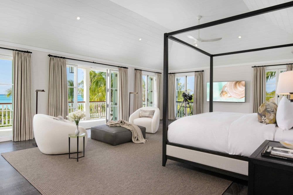 Master bedroom with a four-poster bed and sea-view balcony at Sea Breeze Estate