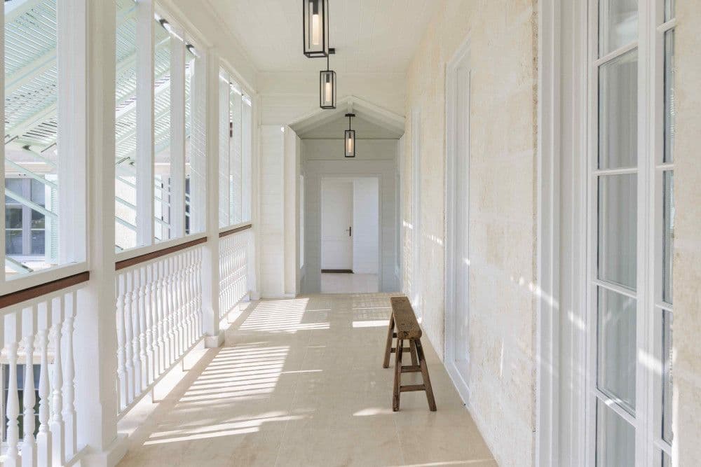 Columned veranda with a white balustrade and coral-stone wall at Sea Breeze Estate