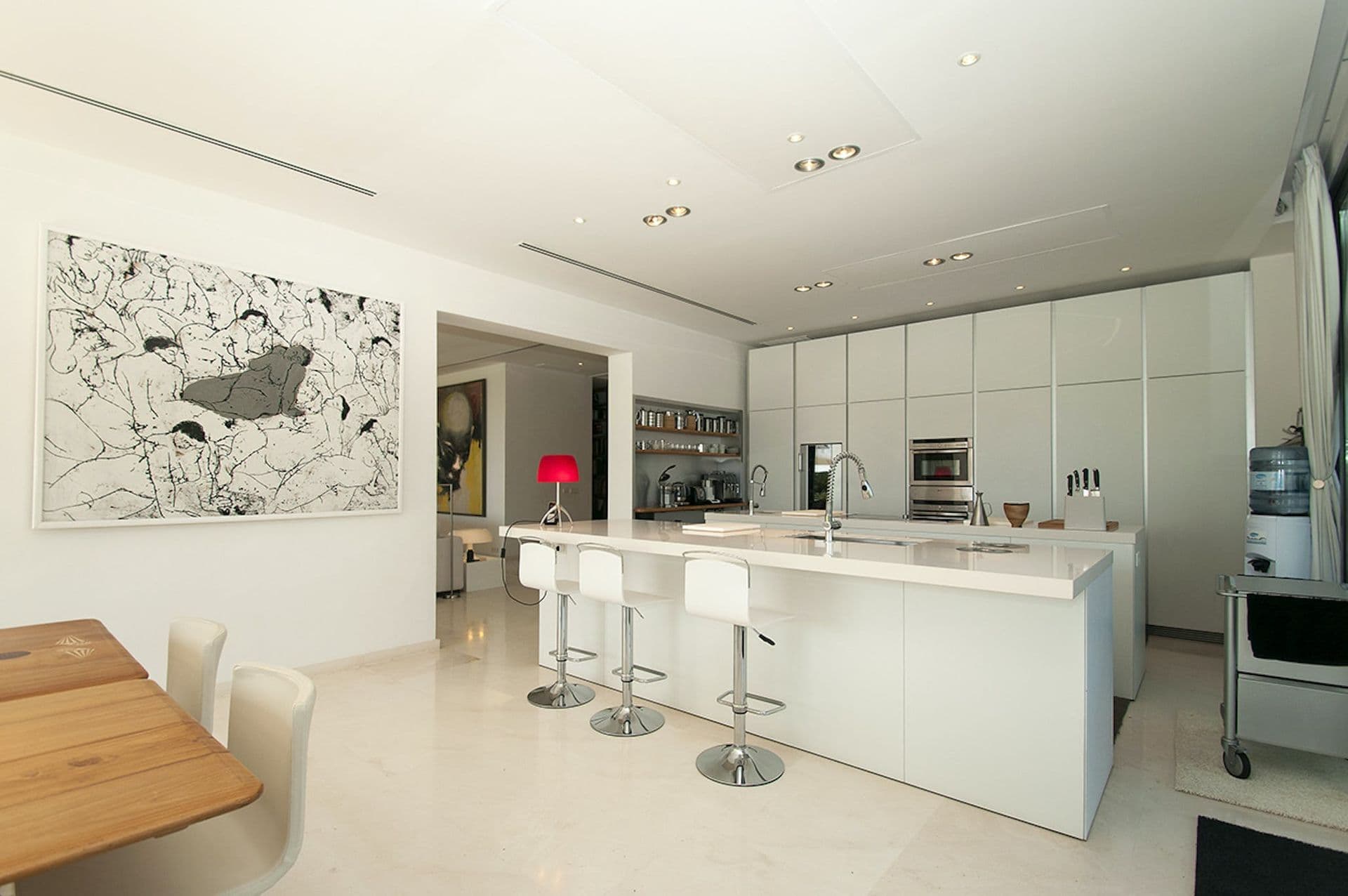 White open-plan kitchen with island and bar stools facing the garden
