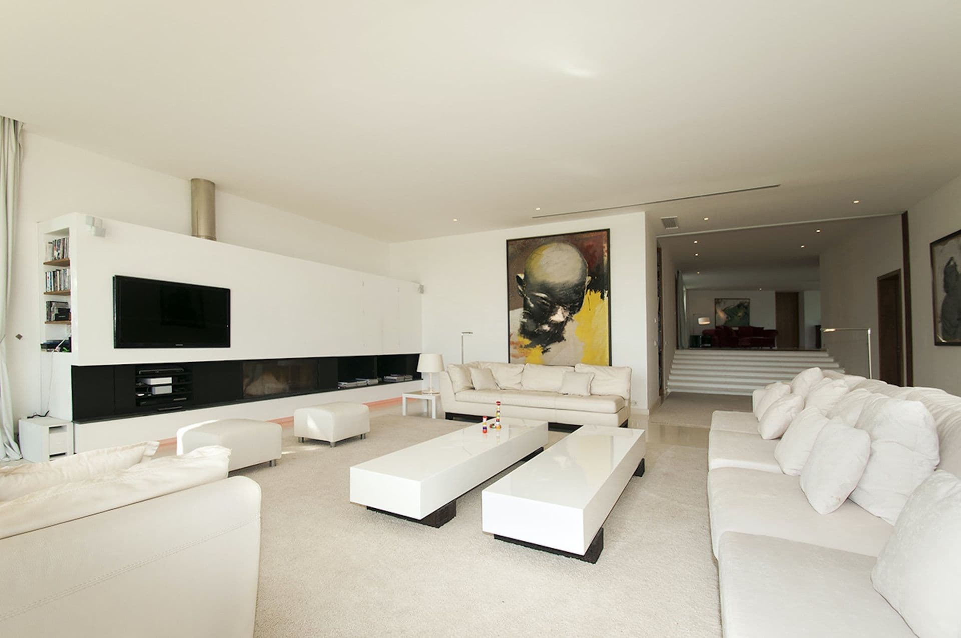 Second lounge area with low white sofas and wall-mounted television
