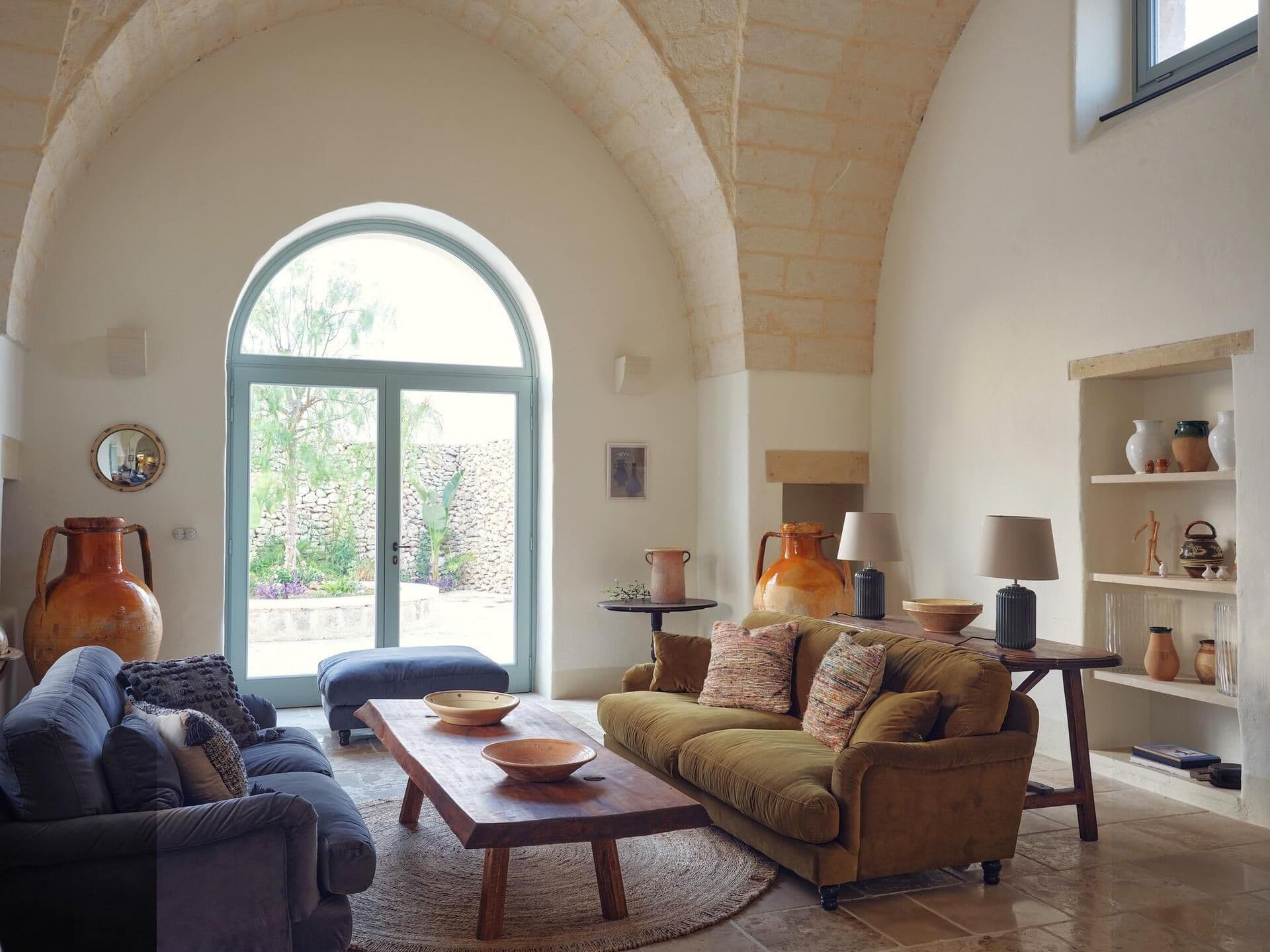 Living room with vaulted ceiling and arched window at Puglian Farmhouse