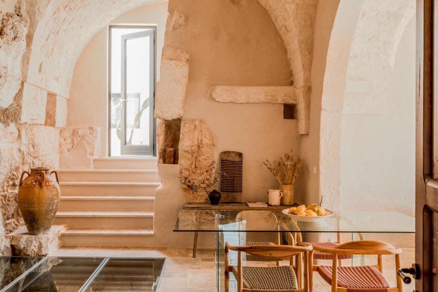 Villa Lucantu dining room with barrel-vaulted stone ceiling and glass table, Cisternino, Puglia, Italy