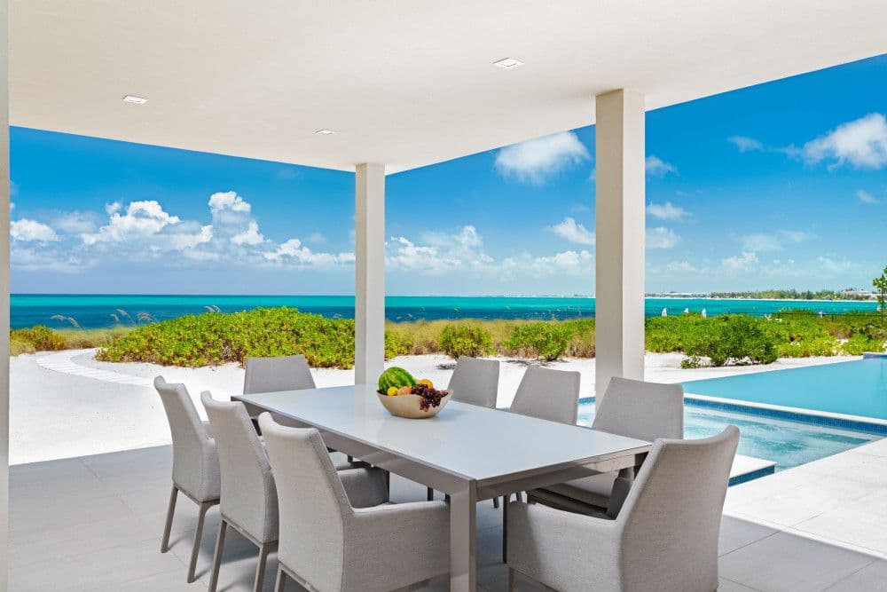 Covered terrace dining framing the beach and ocean at Seaclusion