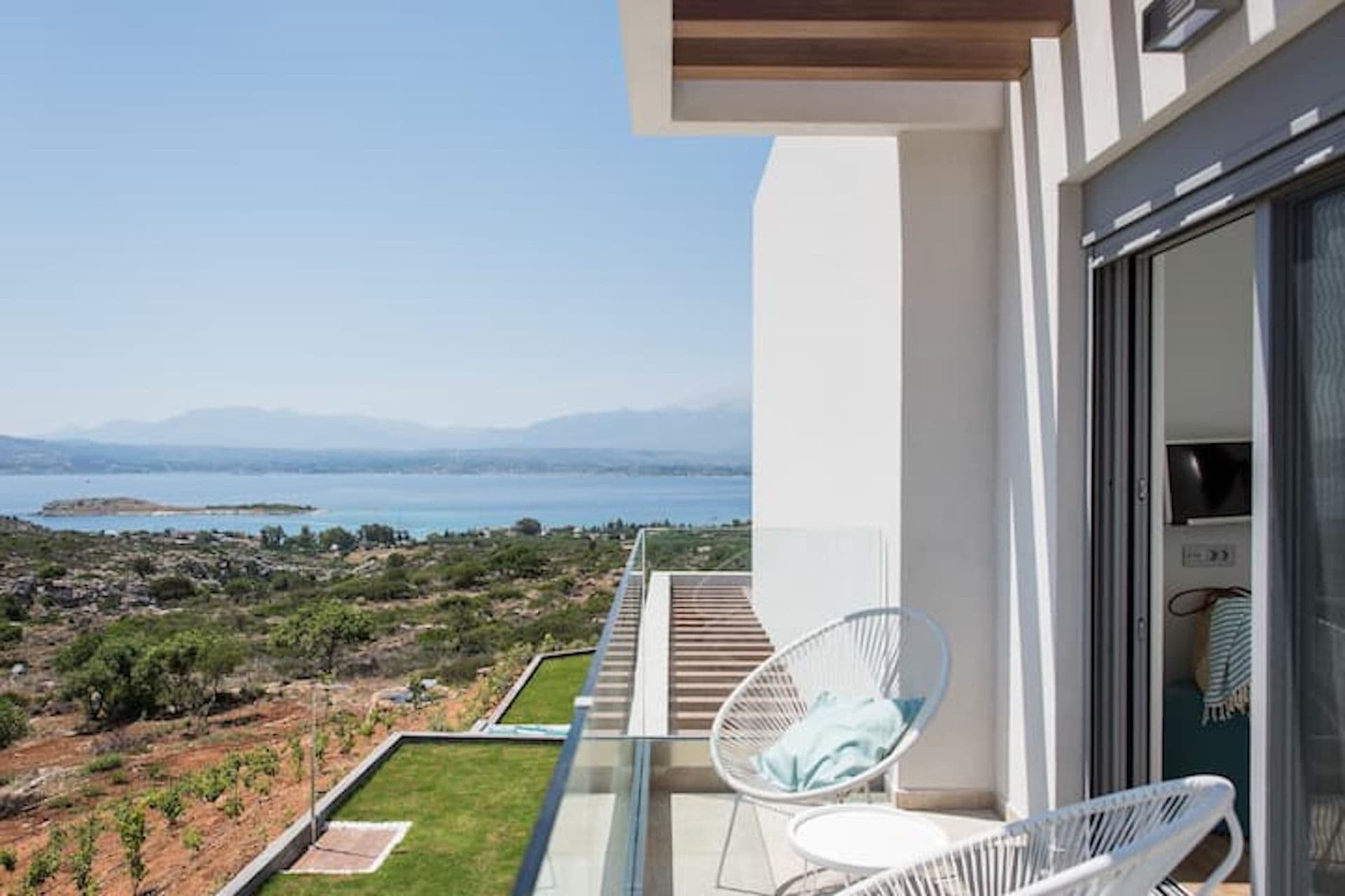 Bedroom balcony with woven chairs framing the sea view at Back to the Sea, Greece