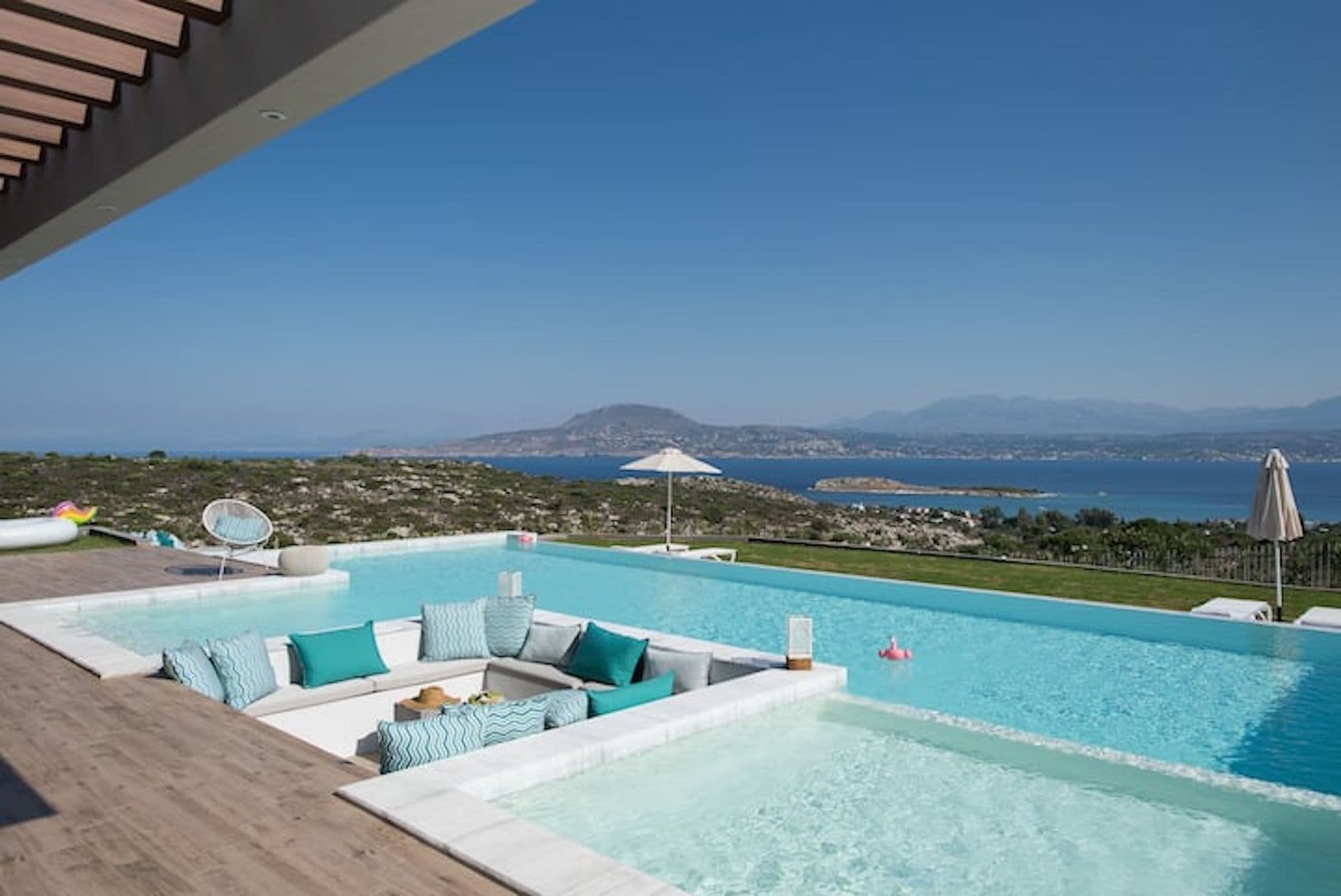 Infinity pool with turquoise cushions looking over the bay at Back to the Sea, Greece