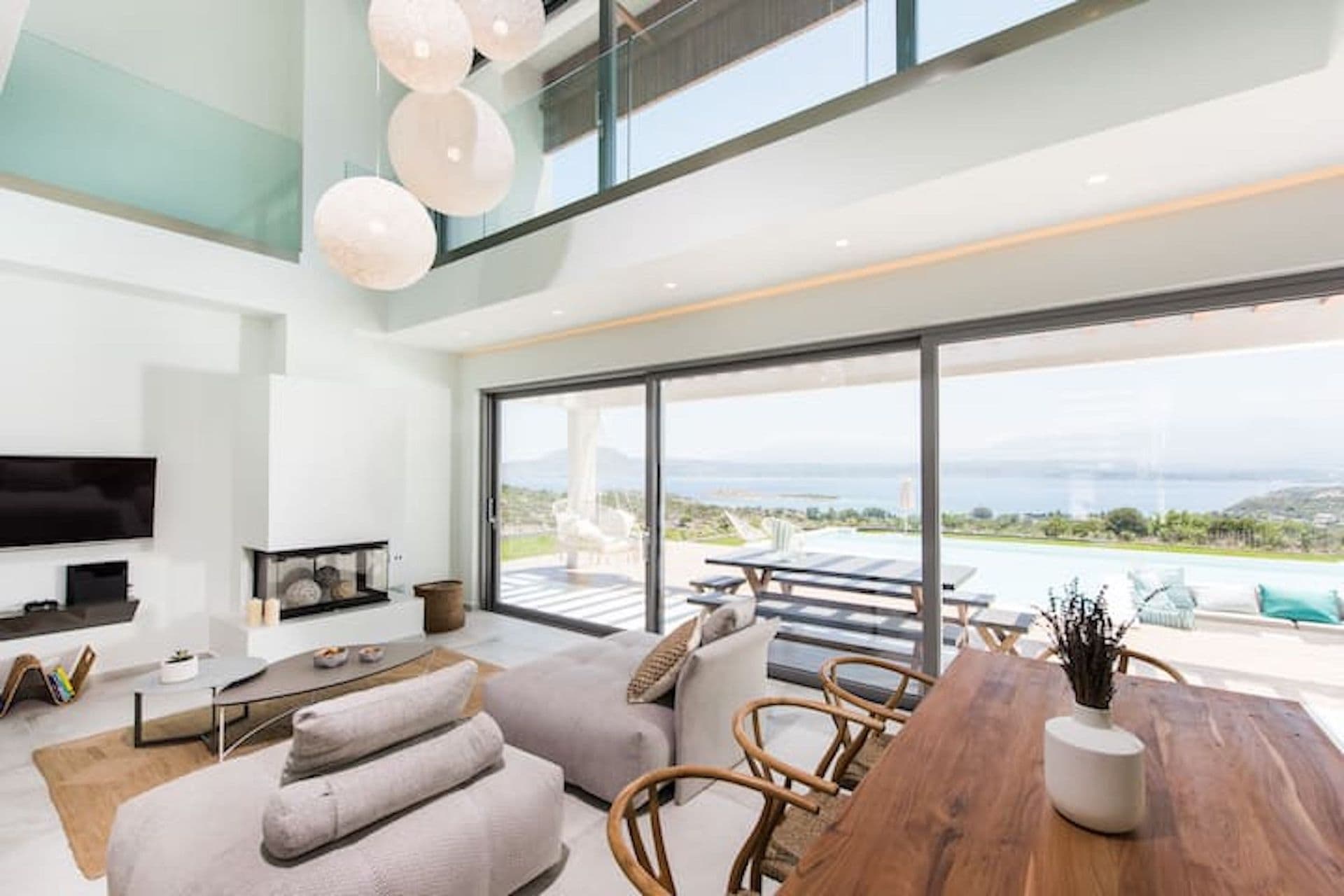 Double-height living room with a fireplace opening to the pool and sea at Back to the Sea, Greece