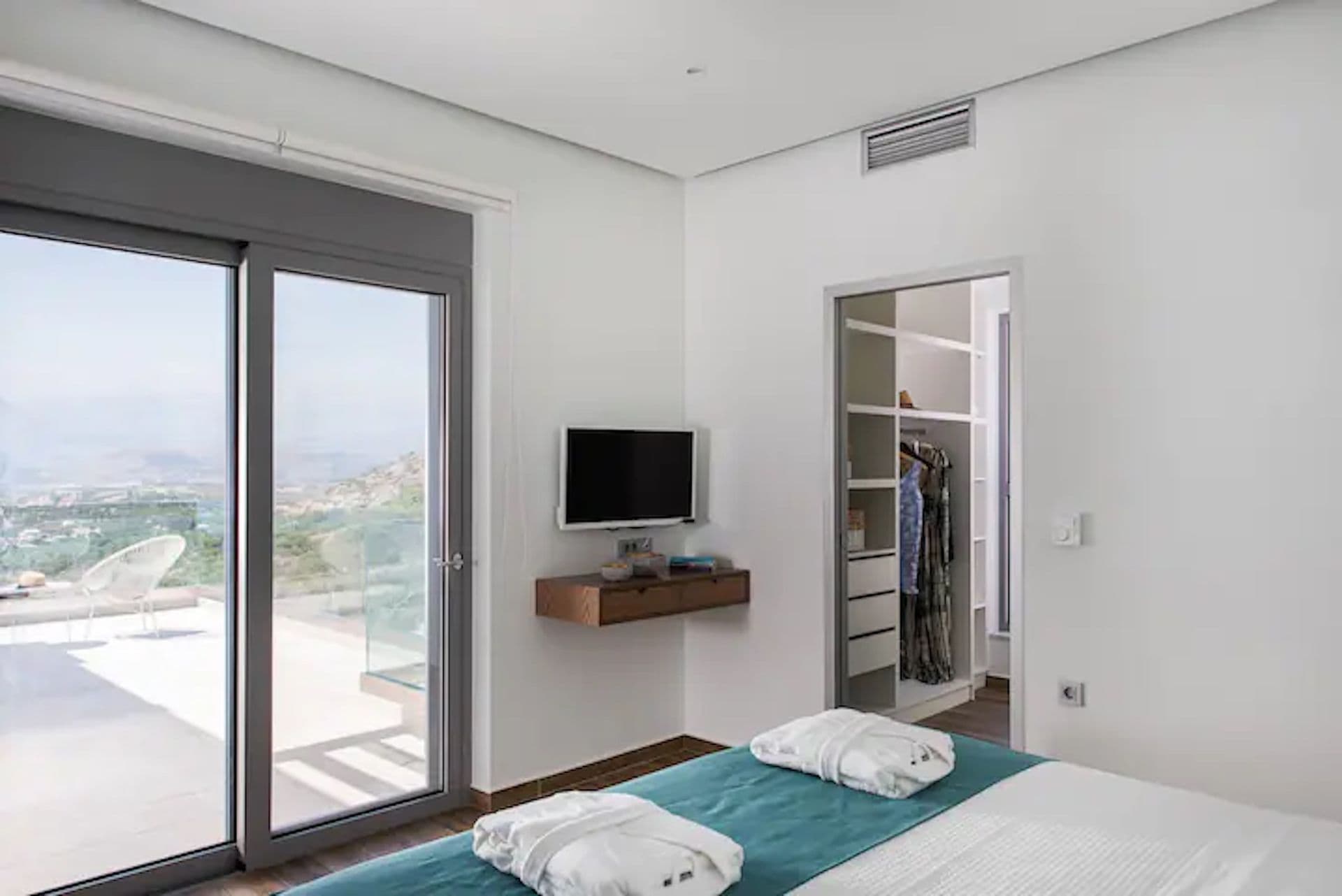 Master bedroom in white and teal with a wall television at Back to the Sea, Greece