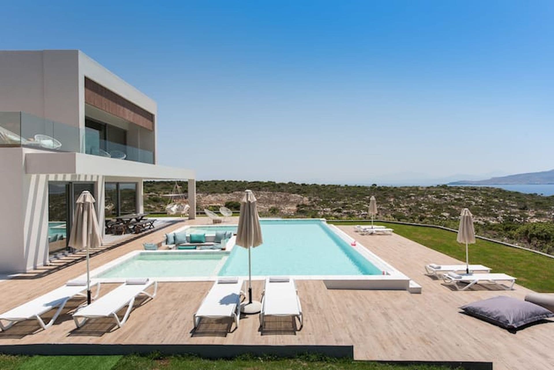 Pool deck with loungers and parasols beside the villa at Back to the Sea, Greece