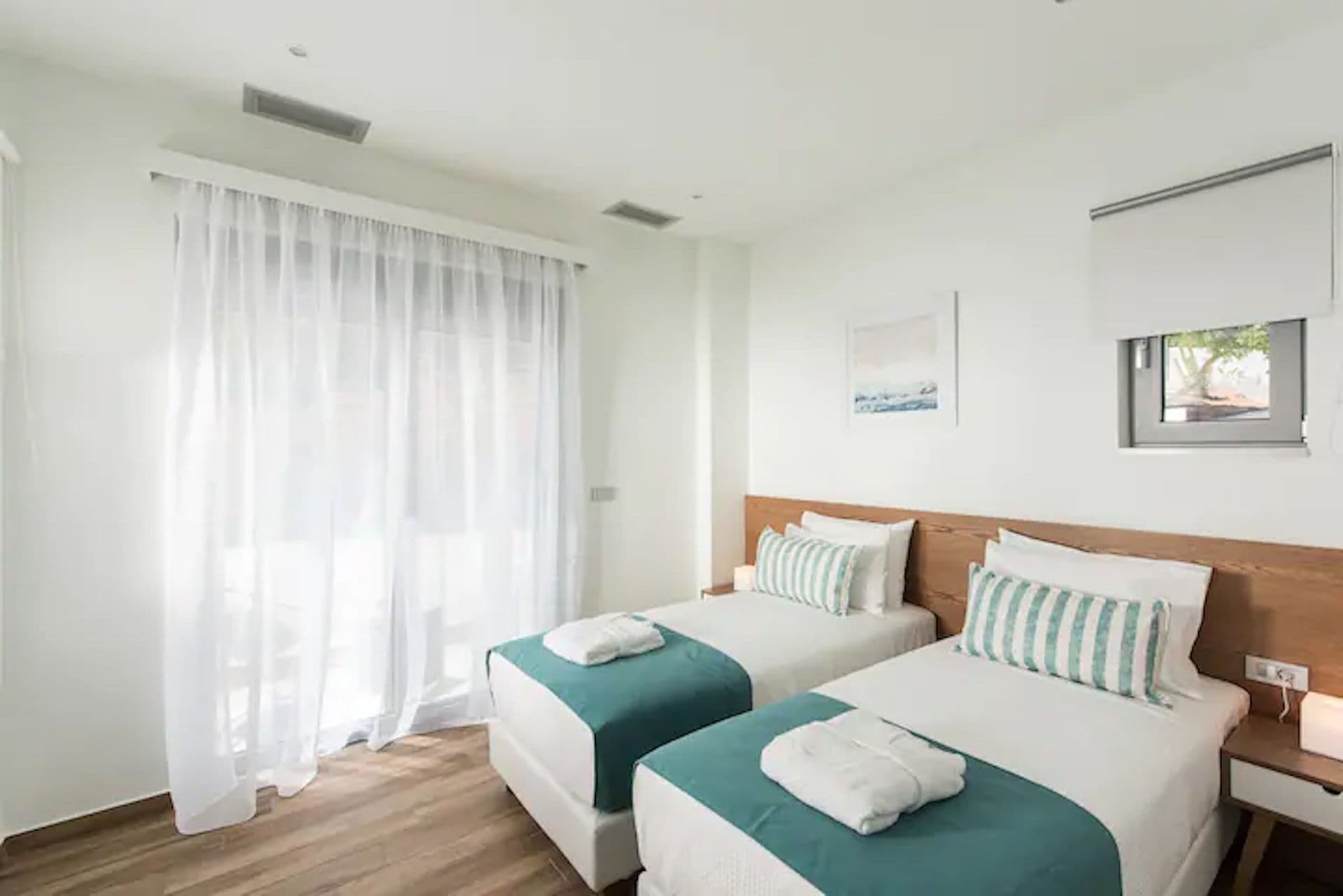 Twin bedroom in white and teal with sheer curtains at Back to the Sea, Greece