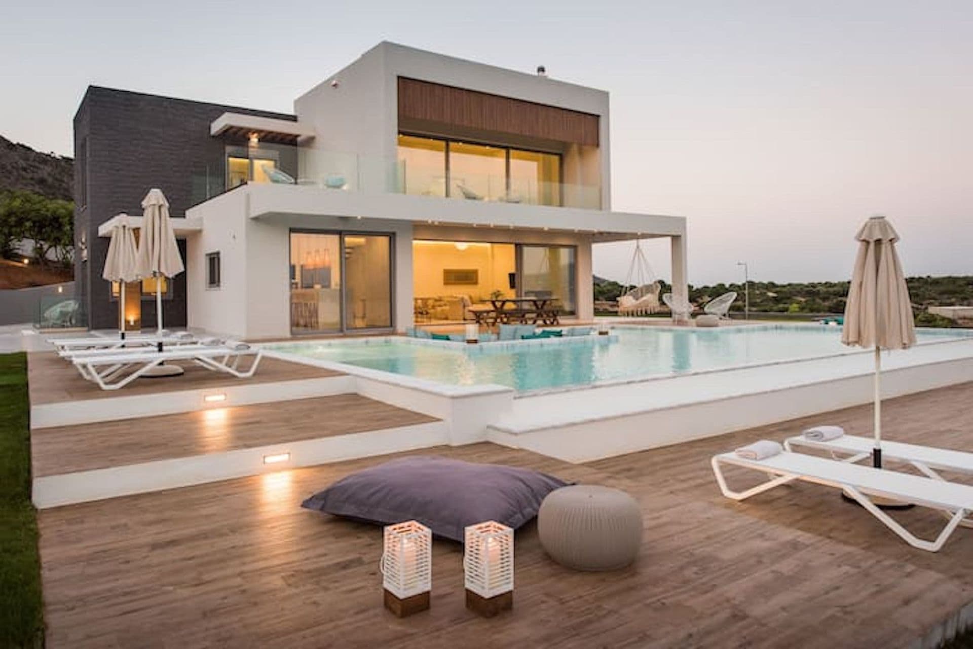 Modern villa glowing at dusk above its lit pool and deck at Back to the Sea, Greece