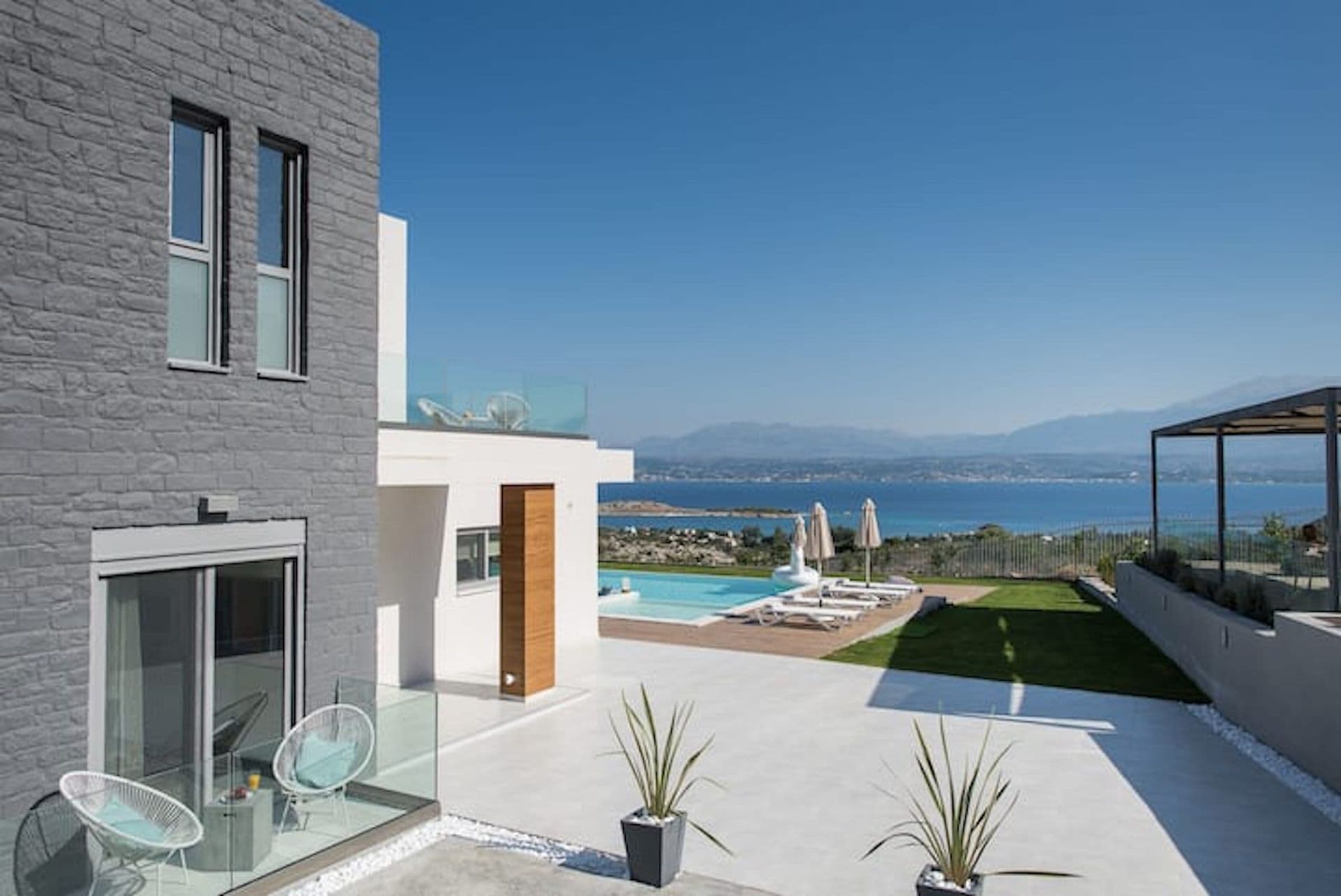 Grey and white cubist villa beside its pool with a bay view at Back to the Sea, Greece