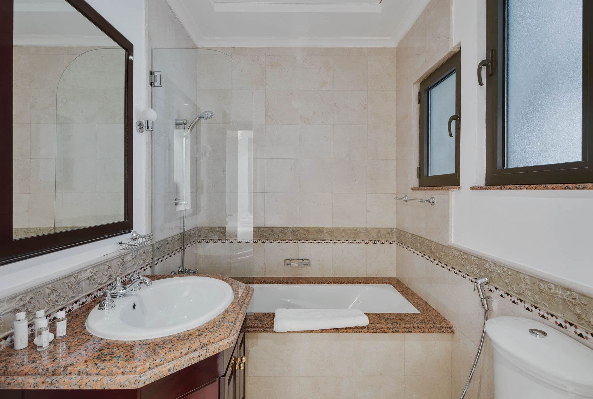 En-suite bathroom with a corner bathtub and mosaic tile border.
