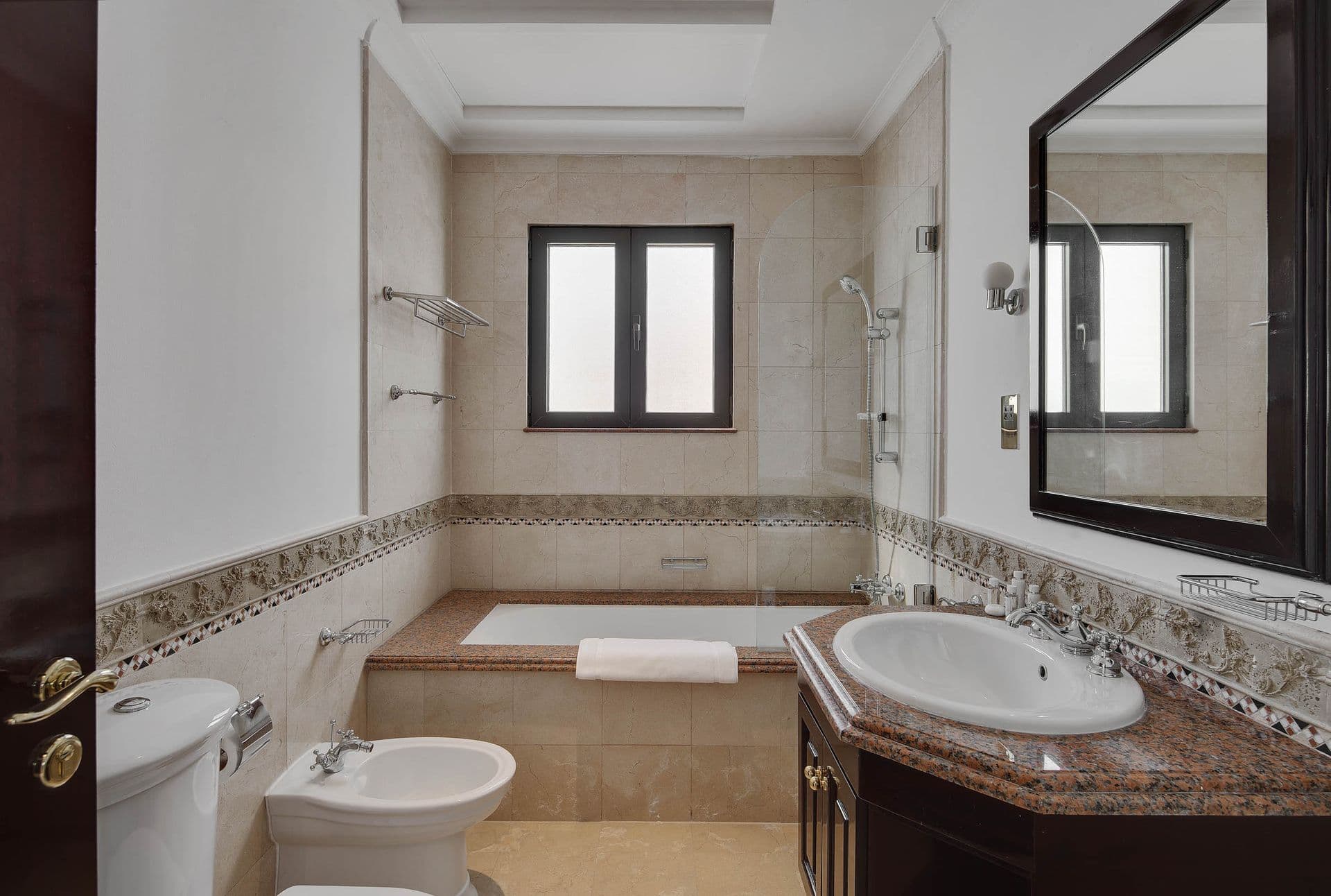 Marble-tiled en-suite with a soaking tub beneath a window.