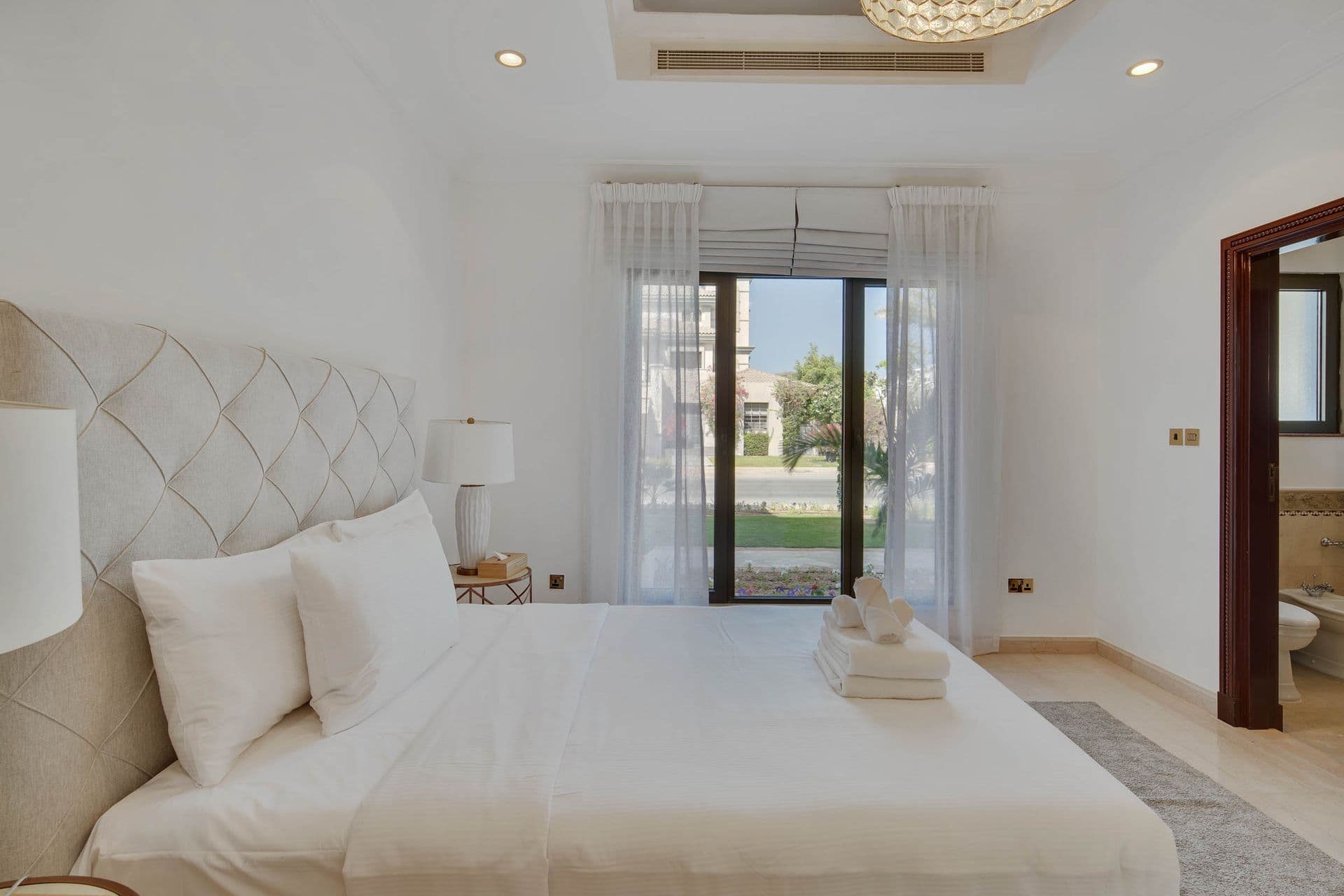 Guest bedroom with a quilted diamond headboard and garden-facing doors.