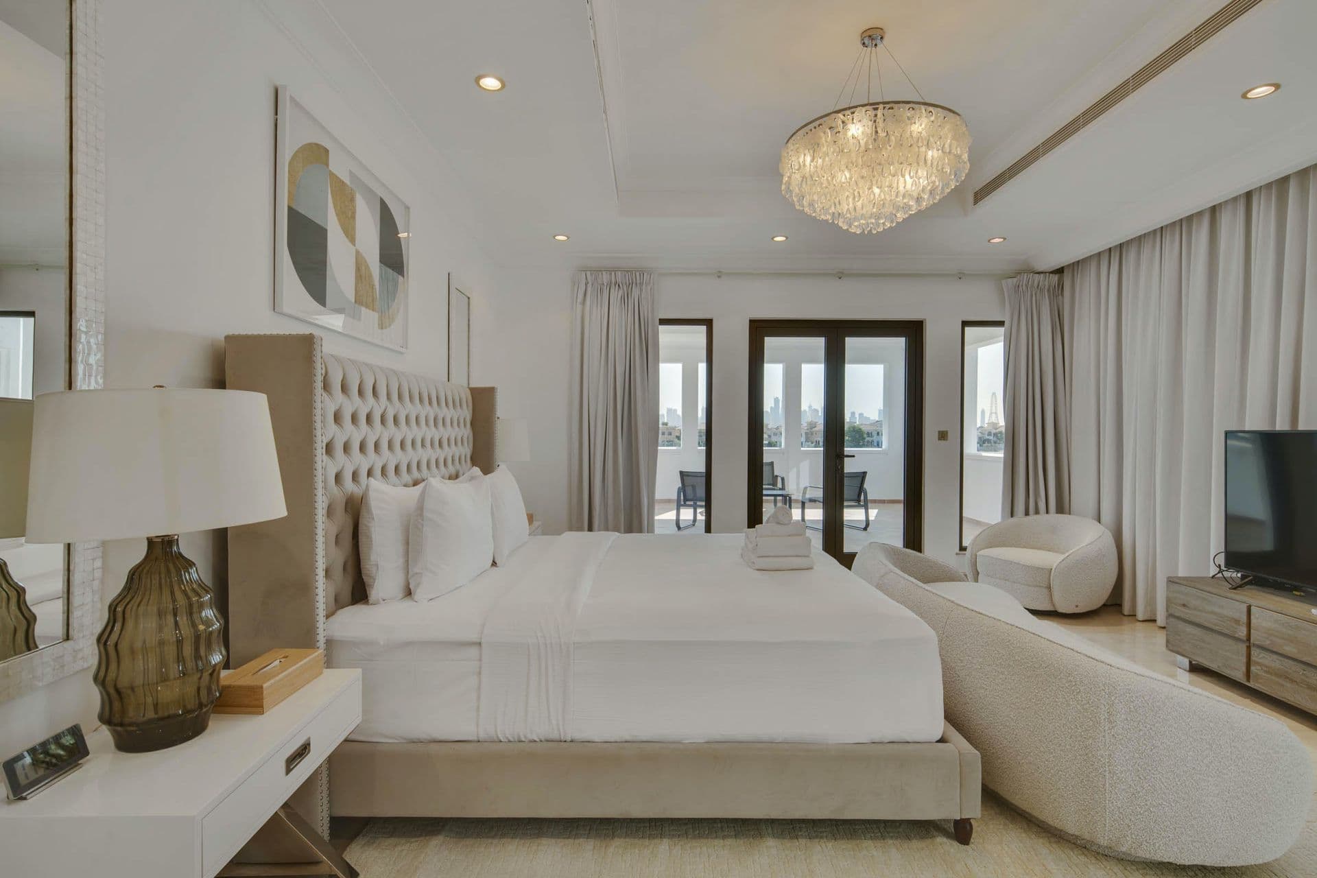 Master bedroom with king bed, chaise lounge and floor-to-ceiling windows.