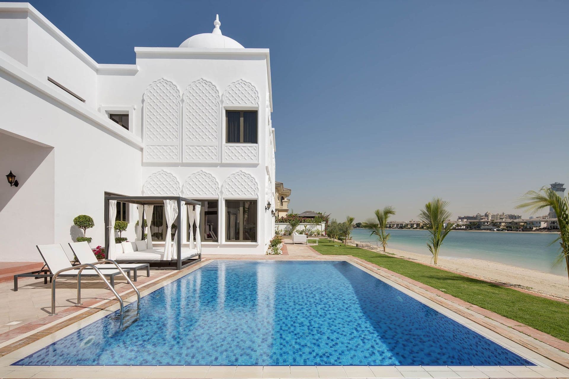 Private infield pool and lawn facing the Dubai Marina skyline at On the Palm villa, Palm Jumeirah.
