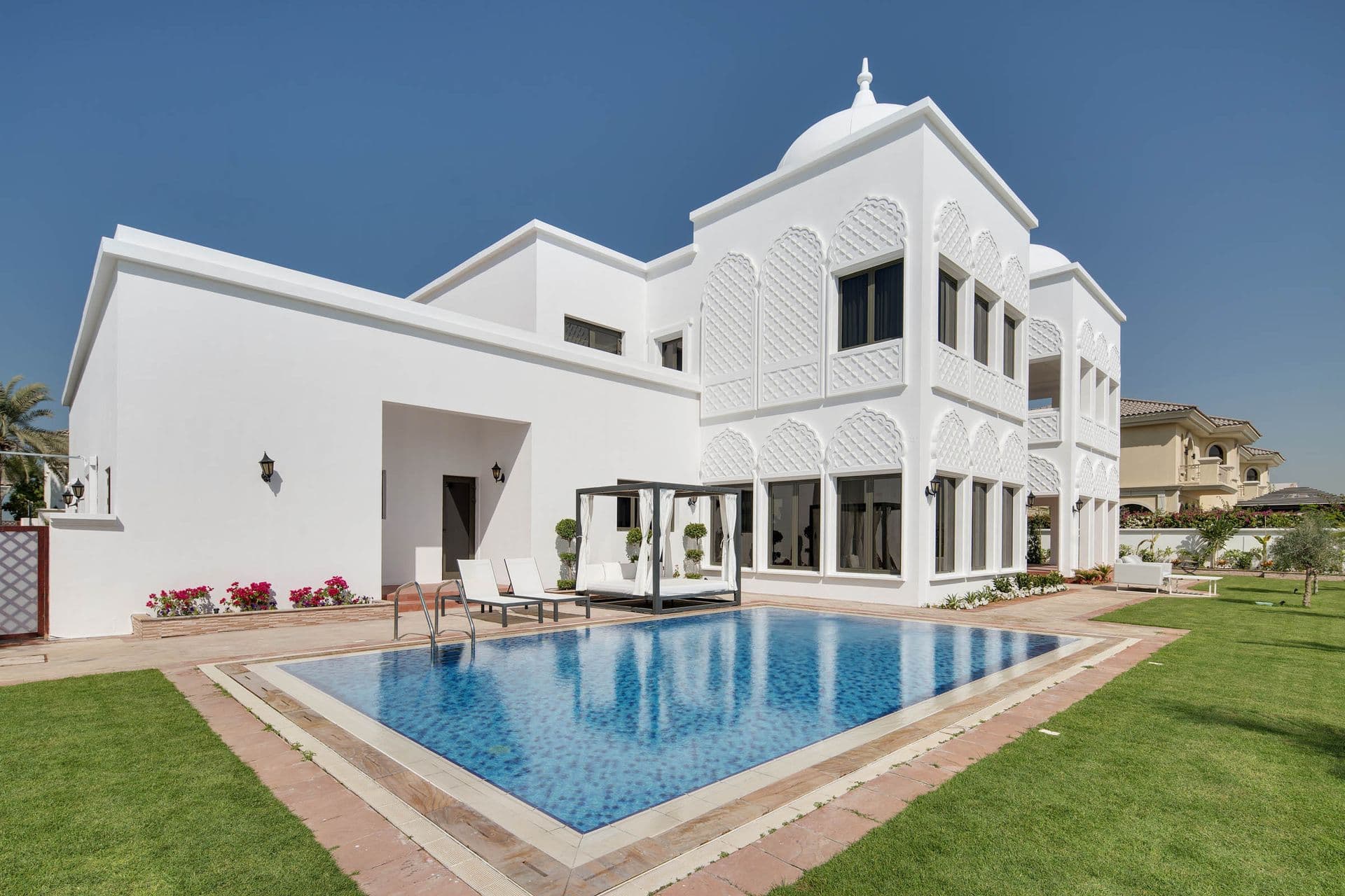 Moorish-style villa facade with private pool and manicured lawn.