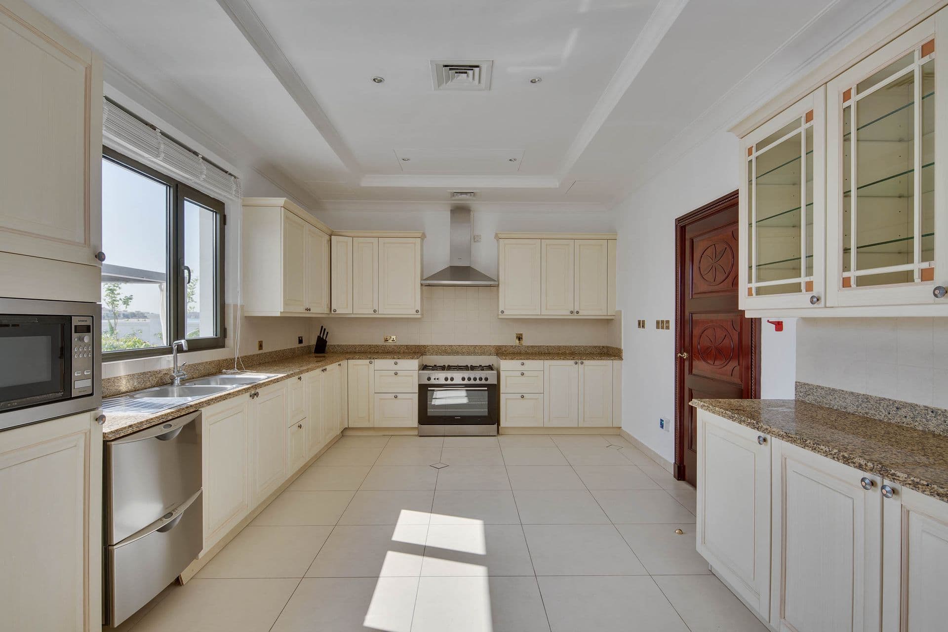 Fully fitted kitchen with cream cabinetry, integrated appliances and marble worktops.