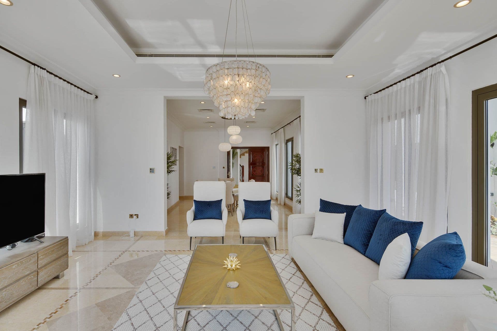 Open-plan living room with cream sofas, navy accent cushions and a marble coffee table.