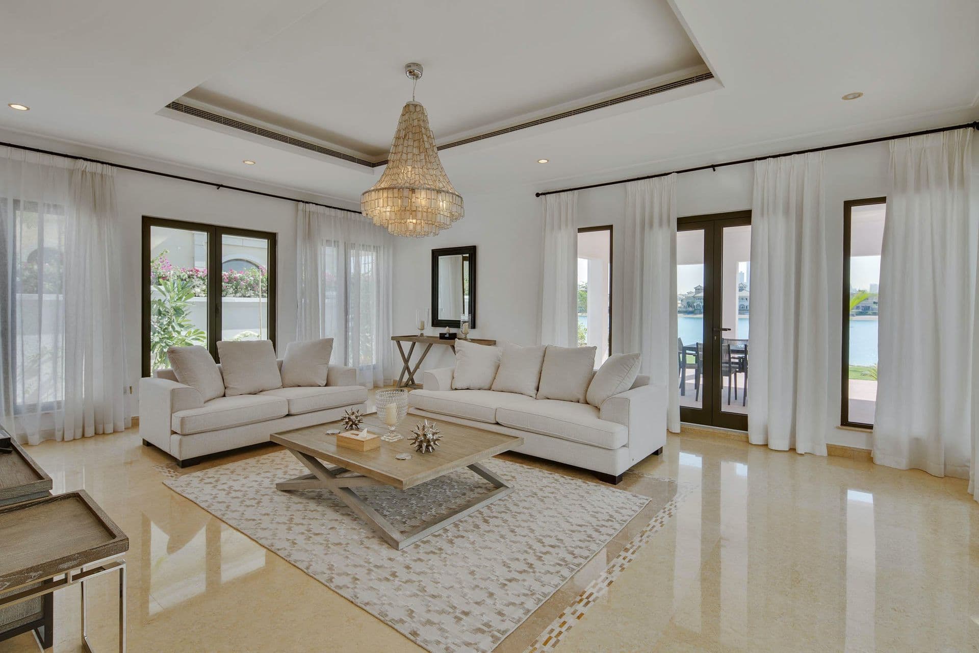 Formal lounge with beaded chandelier and doors opening onto the waterfront terrace.
