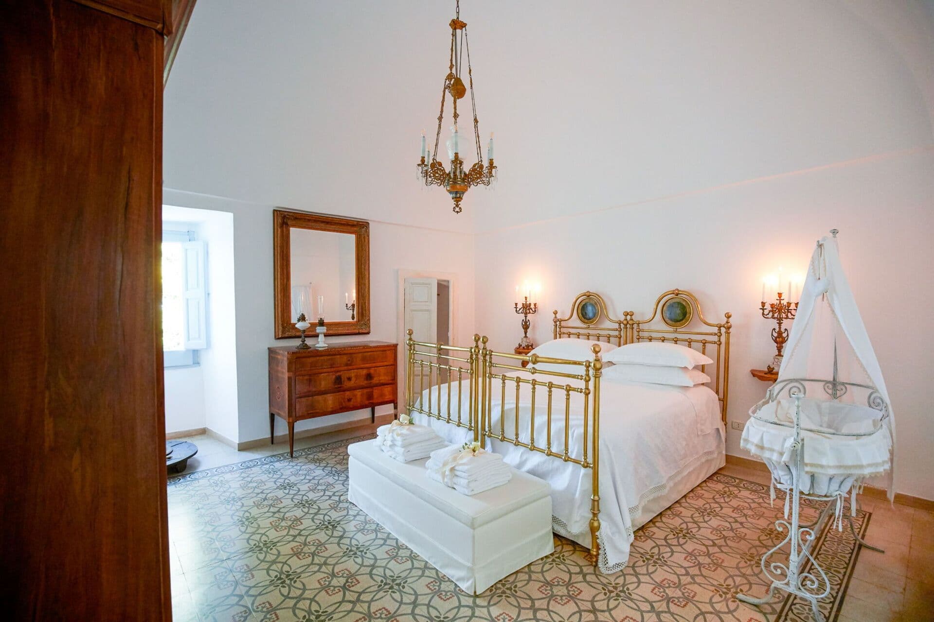 Antique brass framed bed beside a wooden chest in a traditional Puglian bedroom at Mediterranean Sunhouse