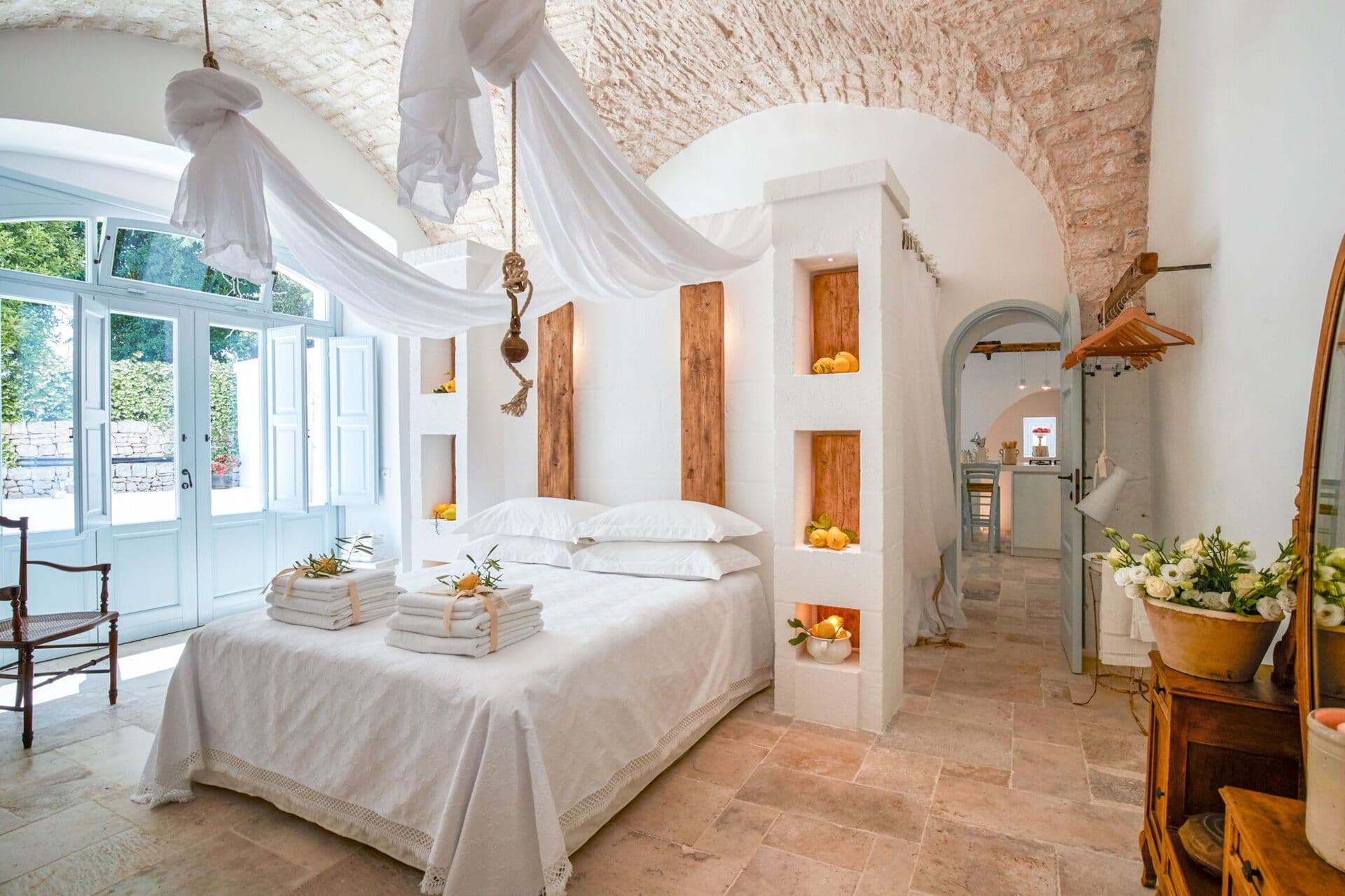 Draped white canopy over a bed set into a stone alcove in a vaulted bedroom at Mediterranean Sunhouse