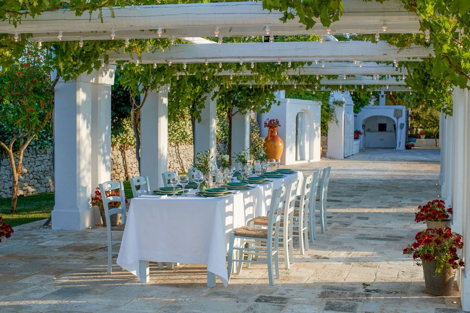 Vine covered stone pergola with a long dining table set for outdoor lunch at Mediterranean Sunhouse in Puglia