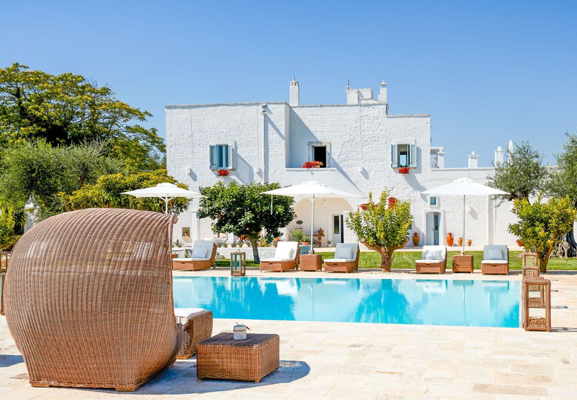 Whitewashed masseria facade in Puglia with sun loungers beside a stone terrace swimming pool at Mediterranean Sunhouse