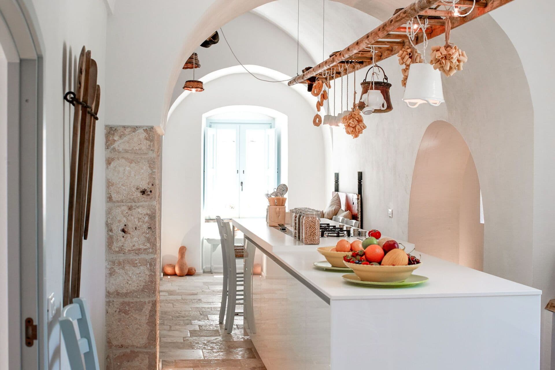 White stone kitchen island with a bowl of fresh fruit in a light filled farmhouse kitchen at Mediterranean Sunhouse