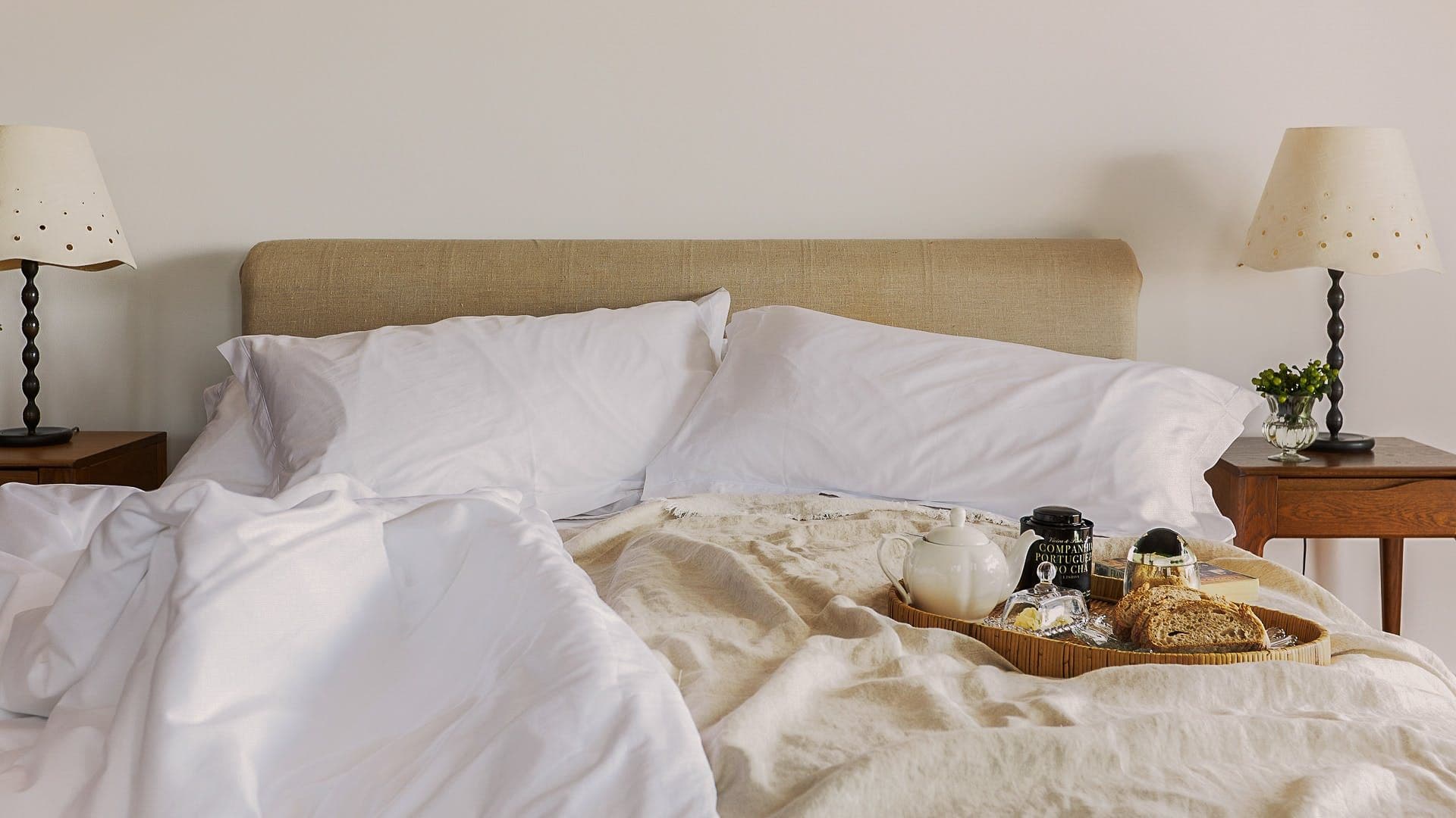 Bedroom dressed in soft white linen with a breakfast tray set on the bed